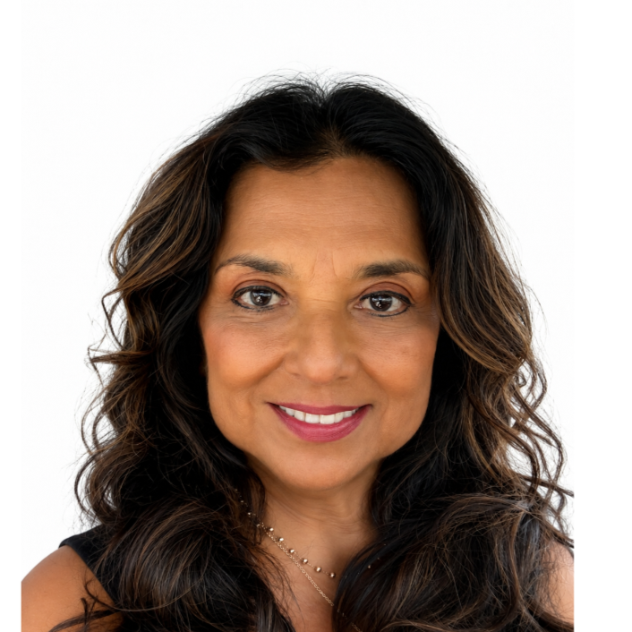A woman with long, wavy dark hair and a warm smile, wearing a sleeveless top and a delicate necklace, against a plain white background.