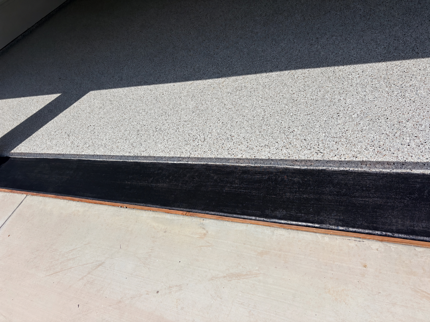 Close-up of a doorway threshold with a black strip, contrasting with light-colored flooring.