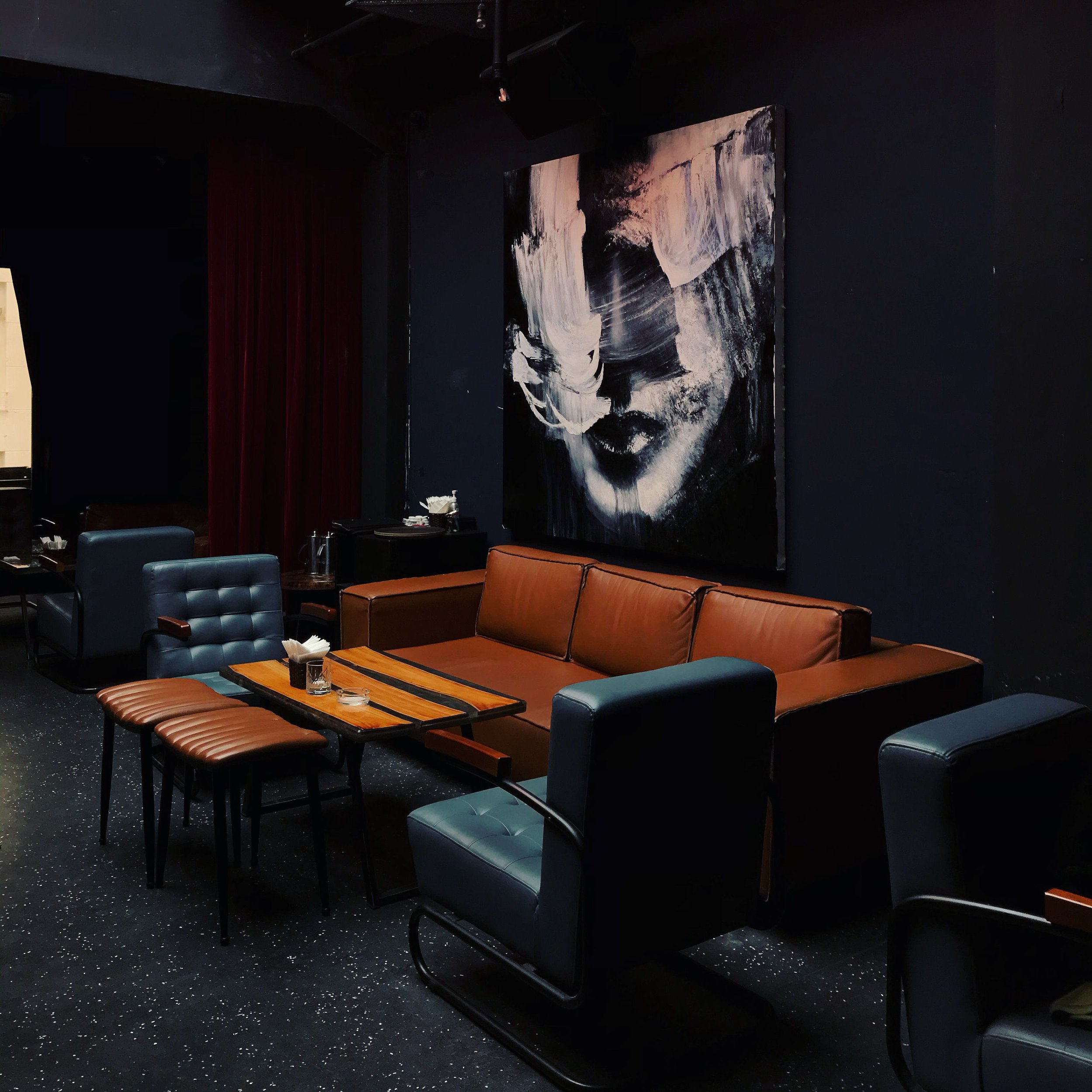 Large-scale expressive portrait painting installed above lounge seating in a hospitality interior — art consulting and installation by Artus Operandi
