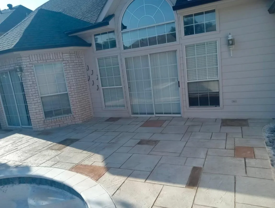 Backyard patio with sliding glass door, large windows, brick and siding house exterior, and a hot tub in the lower left corner.