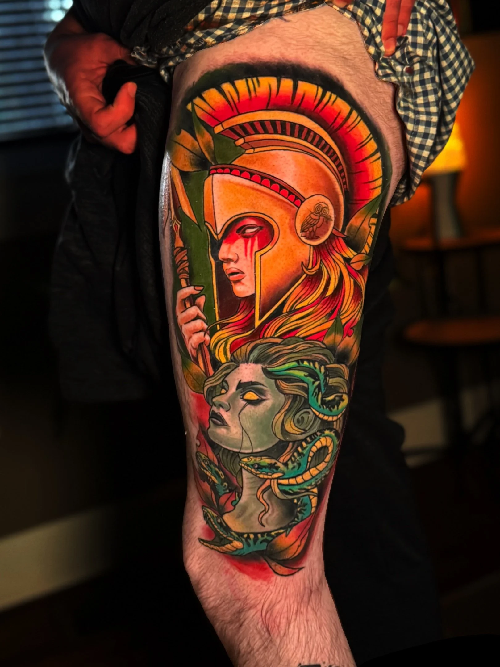 A colorful tattoo on a person's leg depicting various mythological and fantasy-themed characters, including a woman with long hair, a woman with an eye bleeding, and a snake.