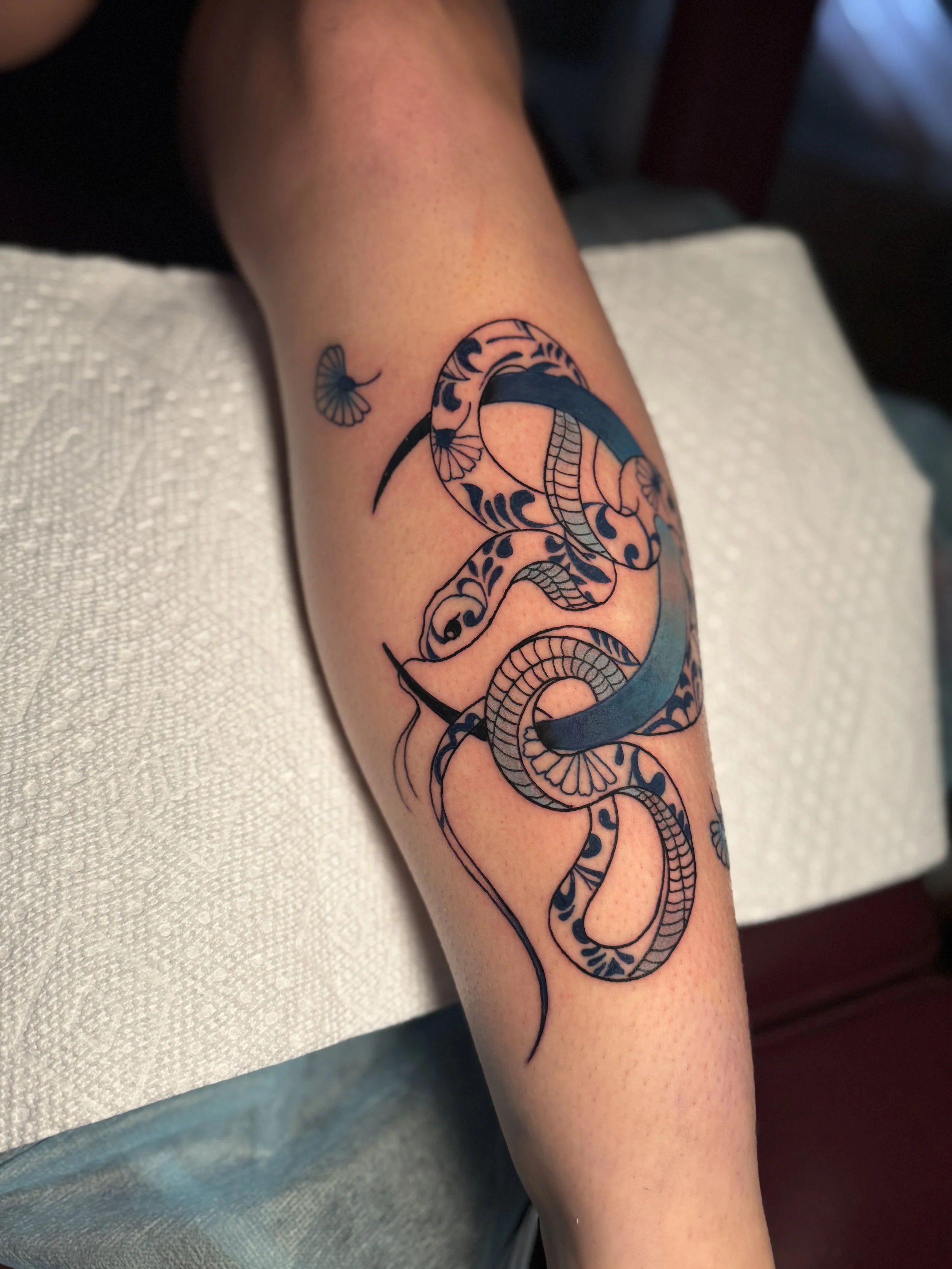 A tattoo of a snake with intricate patterns on a person's forearm.