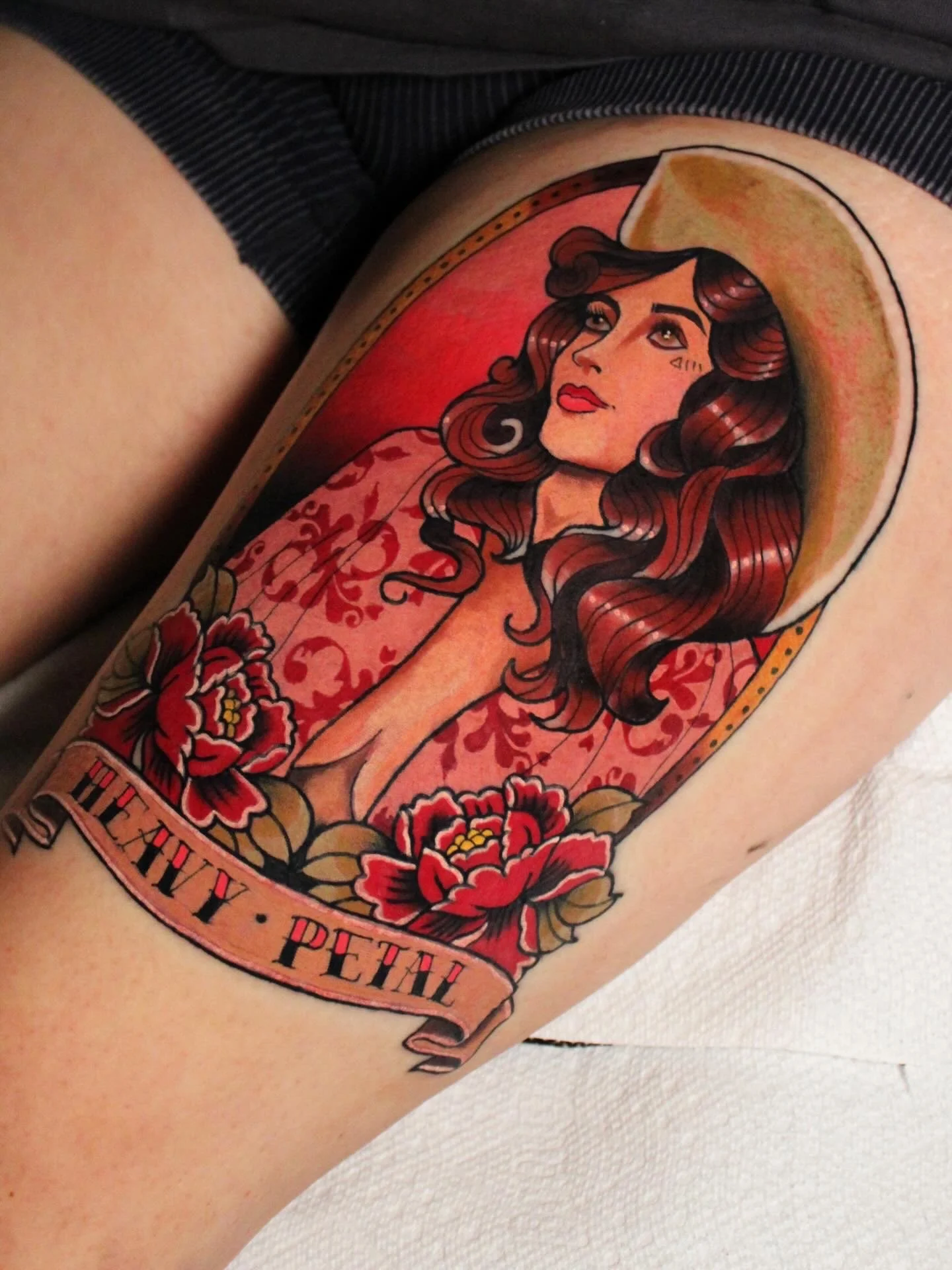 Tattoo of a woman with long dark hair wearing a hat, surrounded by red flowers, with text reading 'PETE' near the bottom.