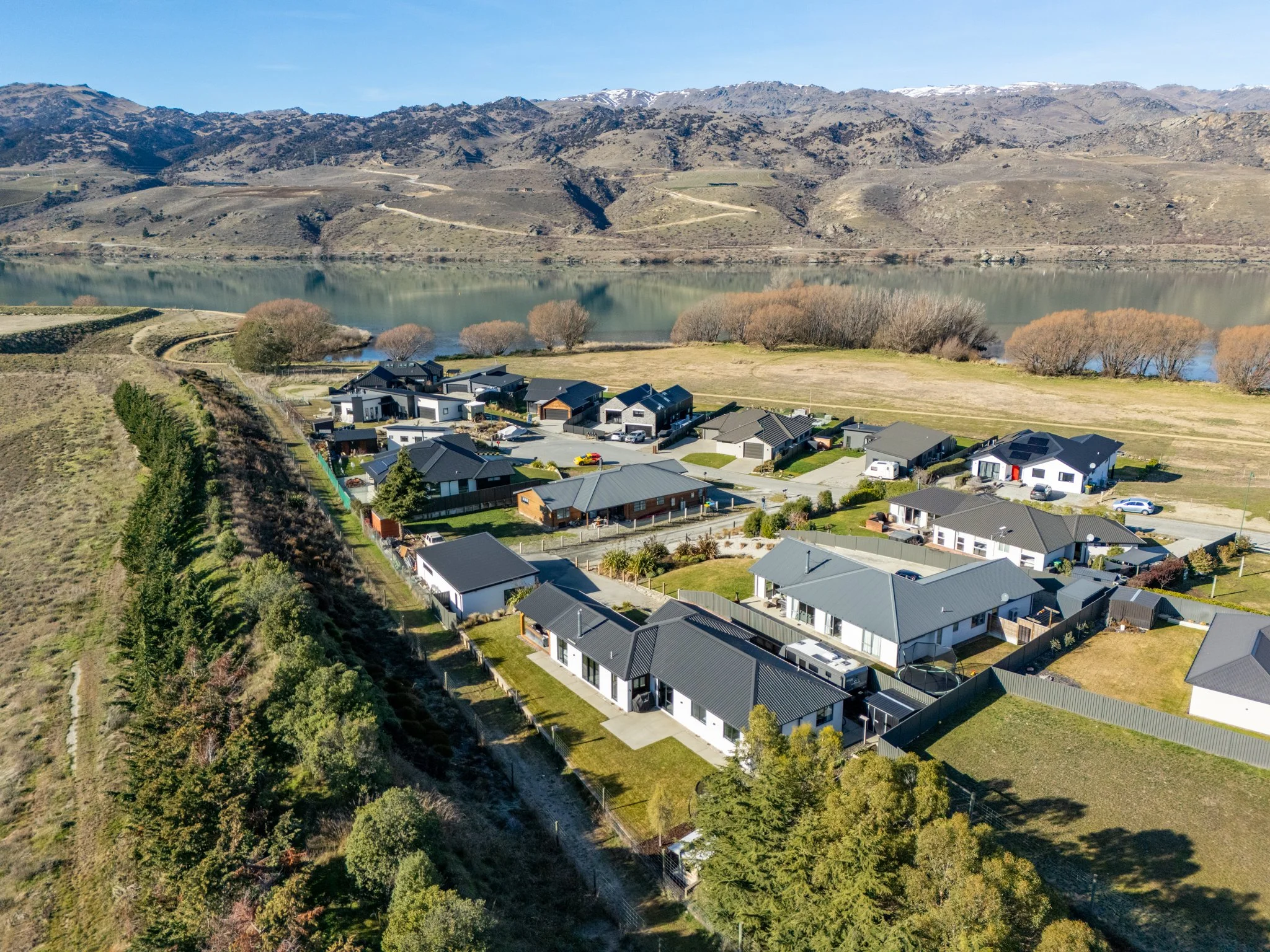 Aerial view of a residential neighborhood near a body of water with hills and mountains in the background.