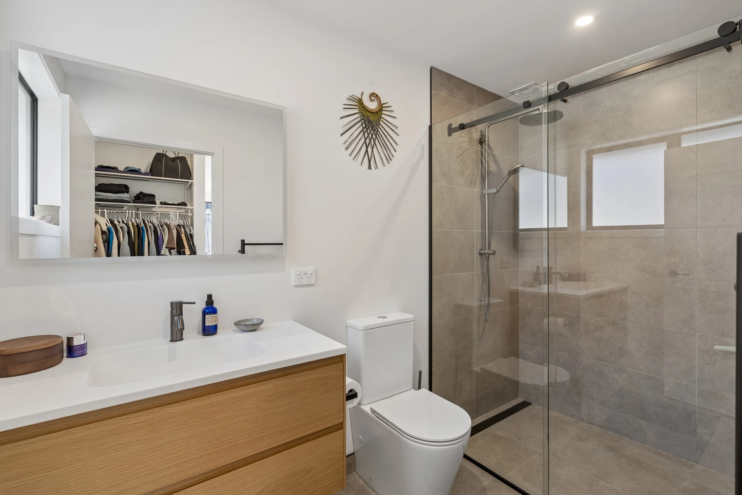 Modern bathroom with vanity, mirror, toilet, and walk-in shower with glass door.