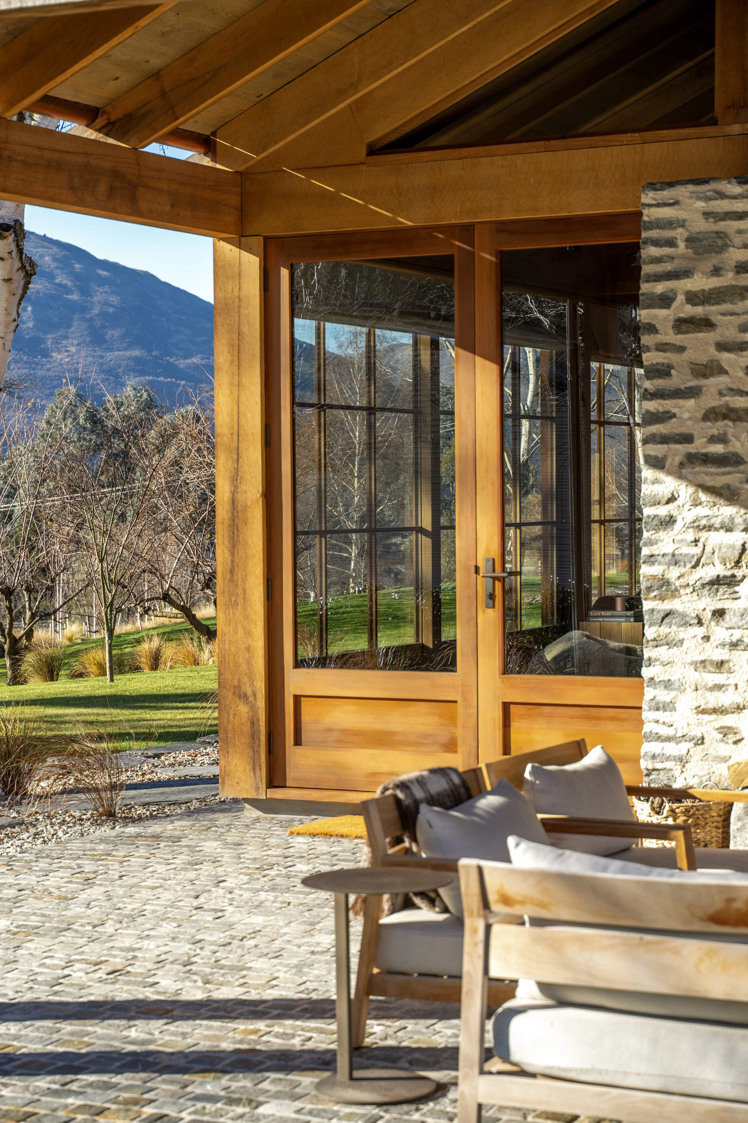 Outdoor patio with modern furniture, stone and wood architecture, mountain view, and clear sunny sky