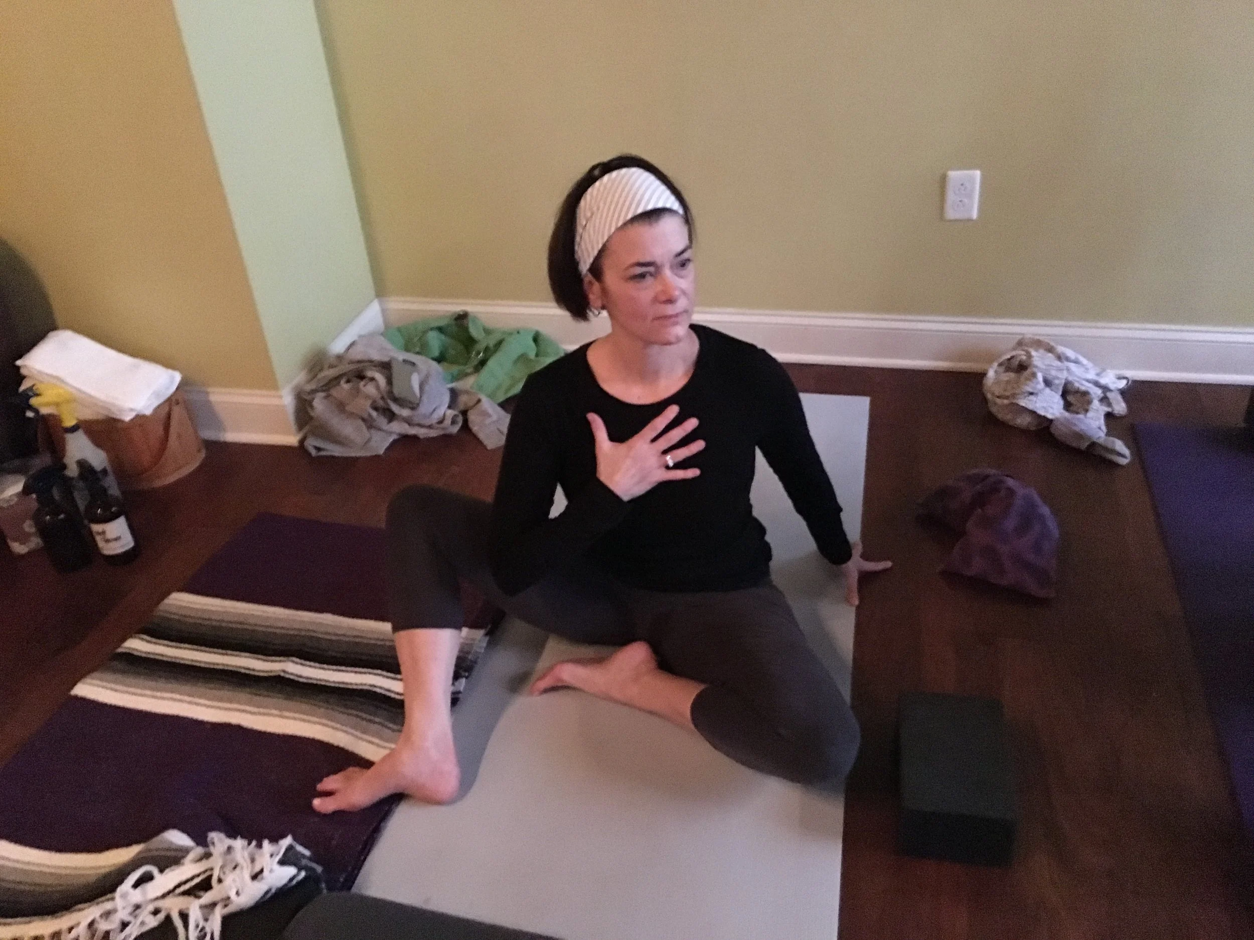 A person seated cross-legged with a hand on their chest, practicing a seated breathing pose