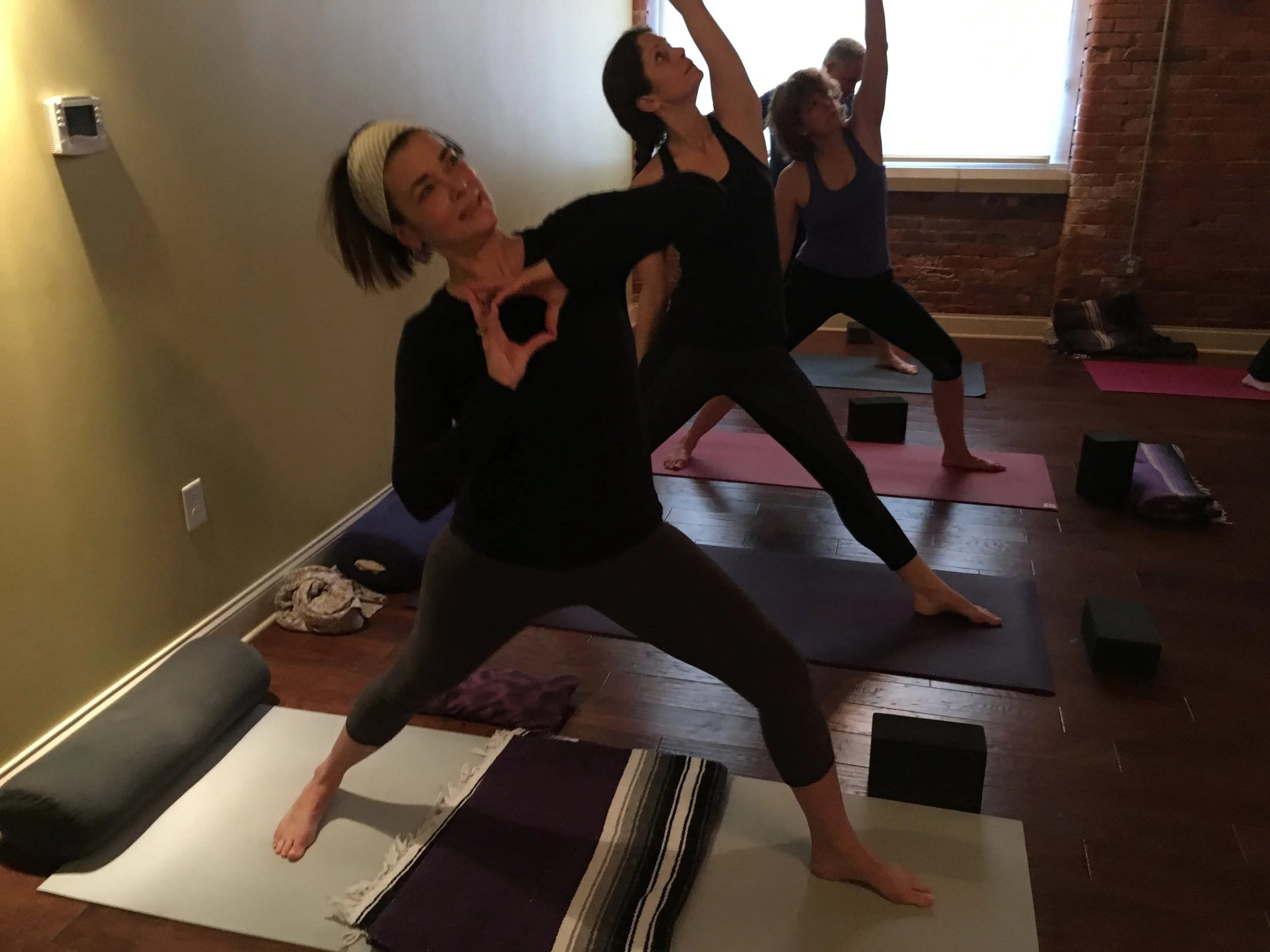 A small yoga class practicing a standing pose in a studio