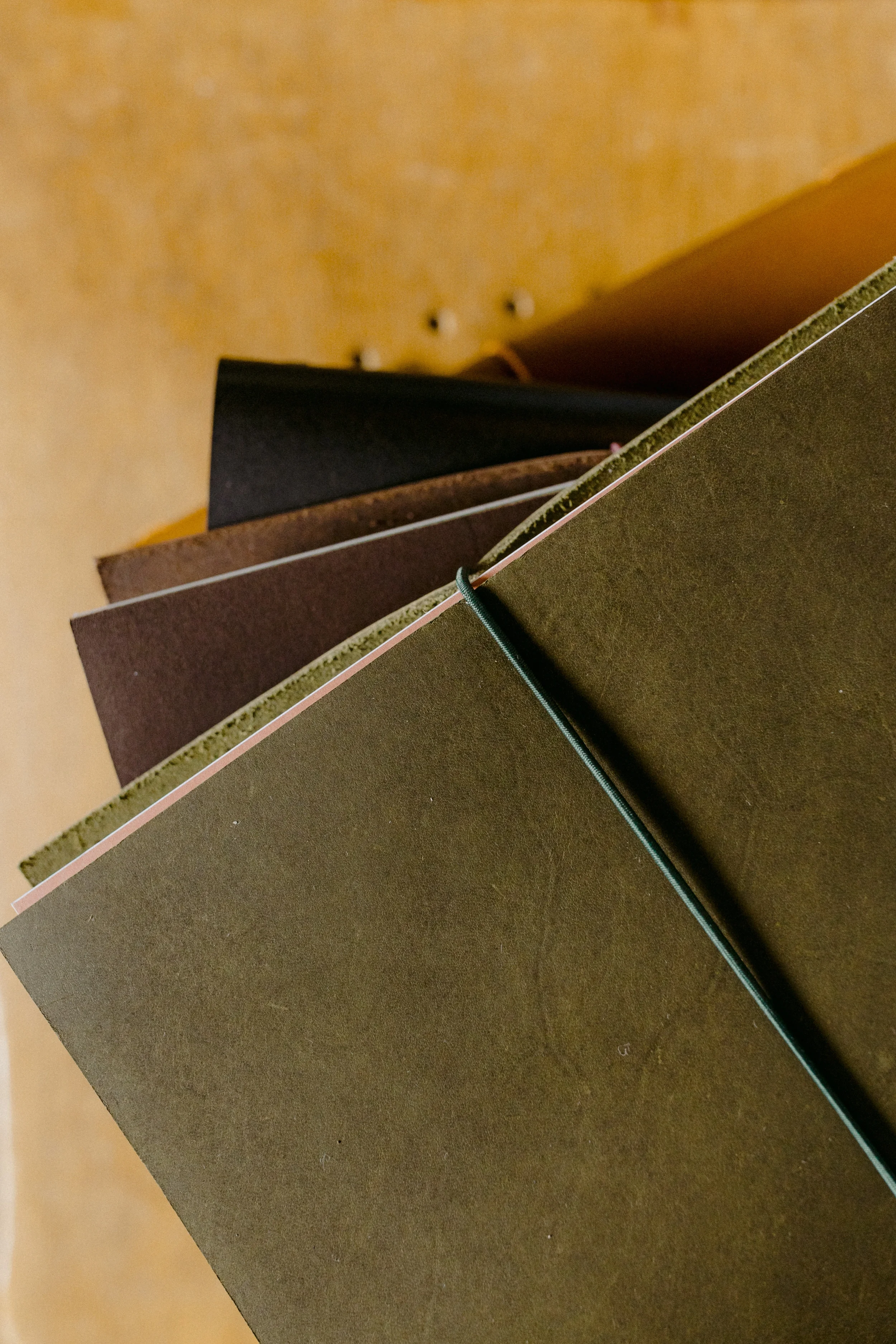 Close-up of stacked cardboard or book covers, with a green elastic band wrapped around the bottom corner.