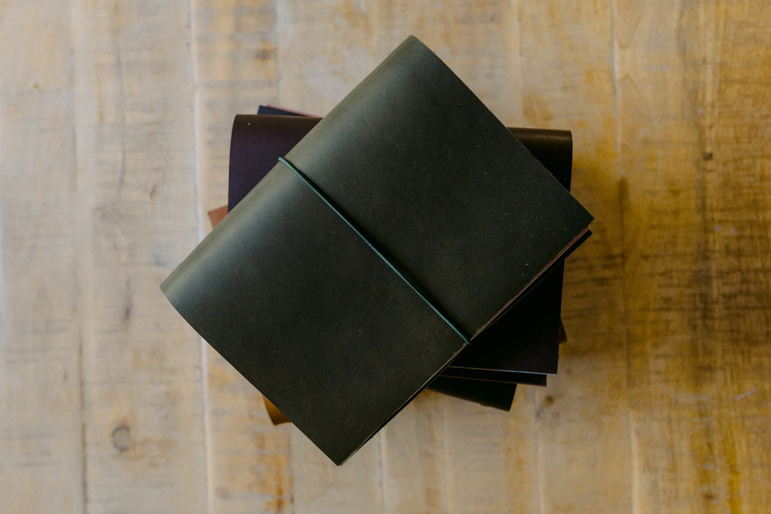 Books stacked on a black surface with a yellow brick wall in the background.