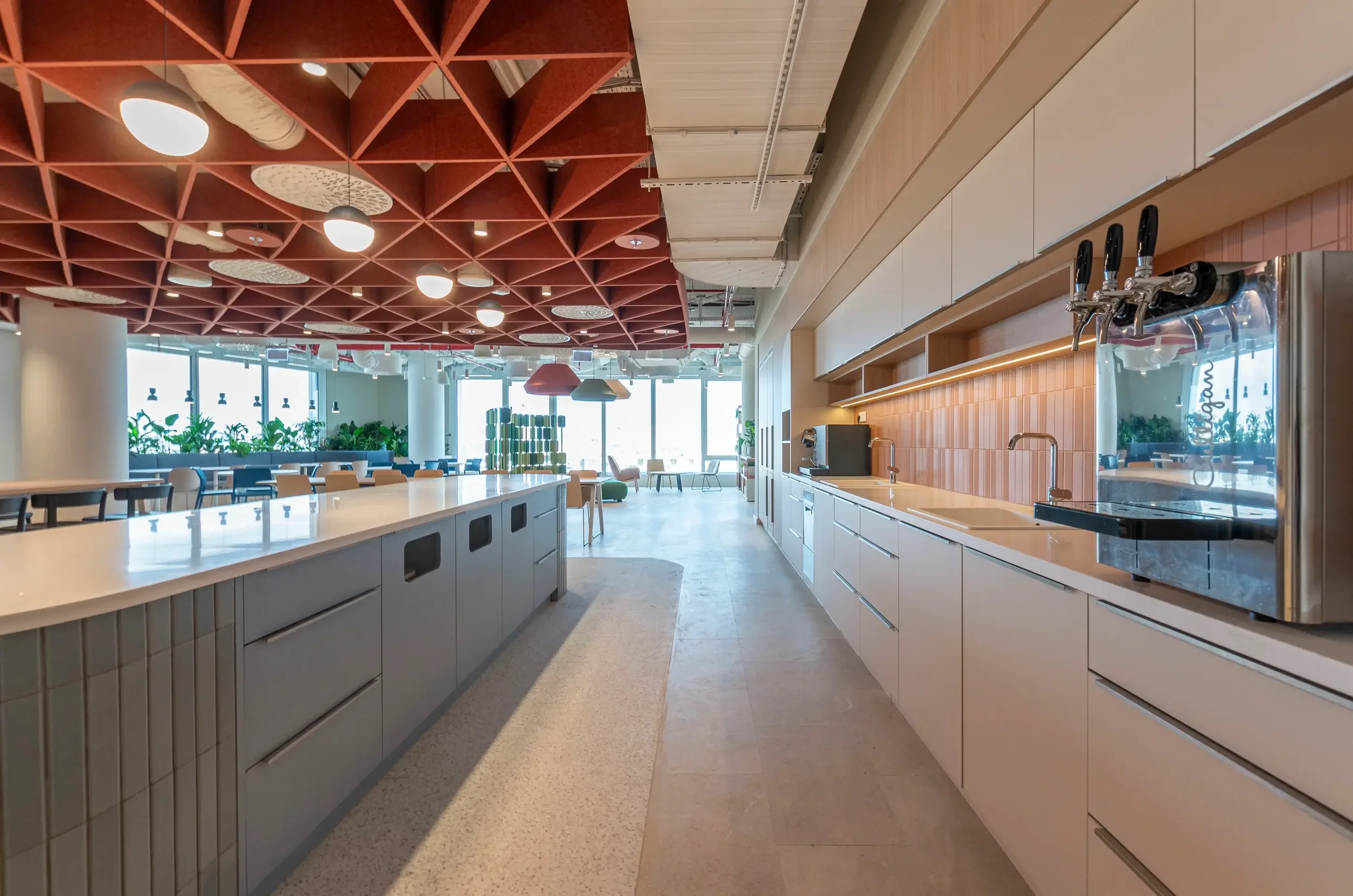 Modern open-concept kitchen and dining area with a red geometric ceiling, white countertops, wooden wall panels, and large windows allowing natural light.
