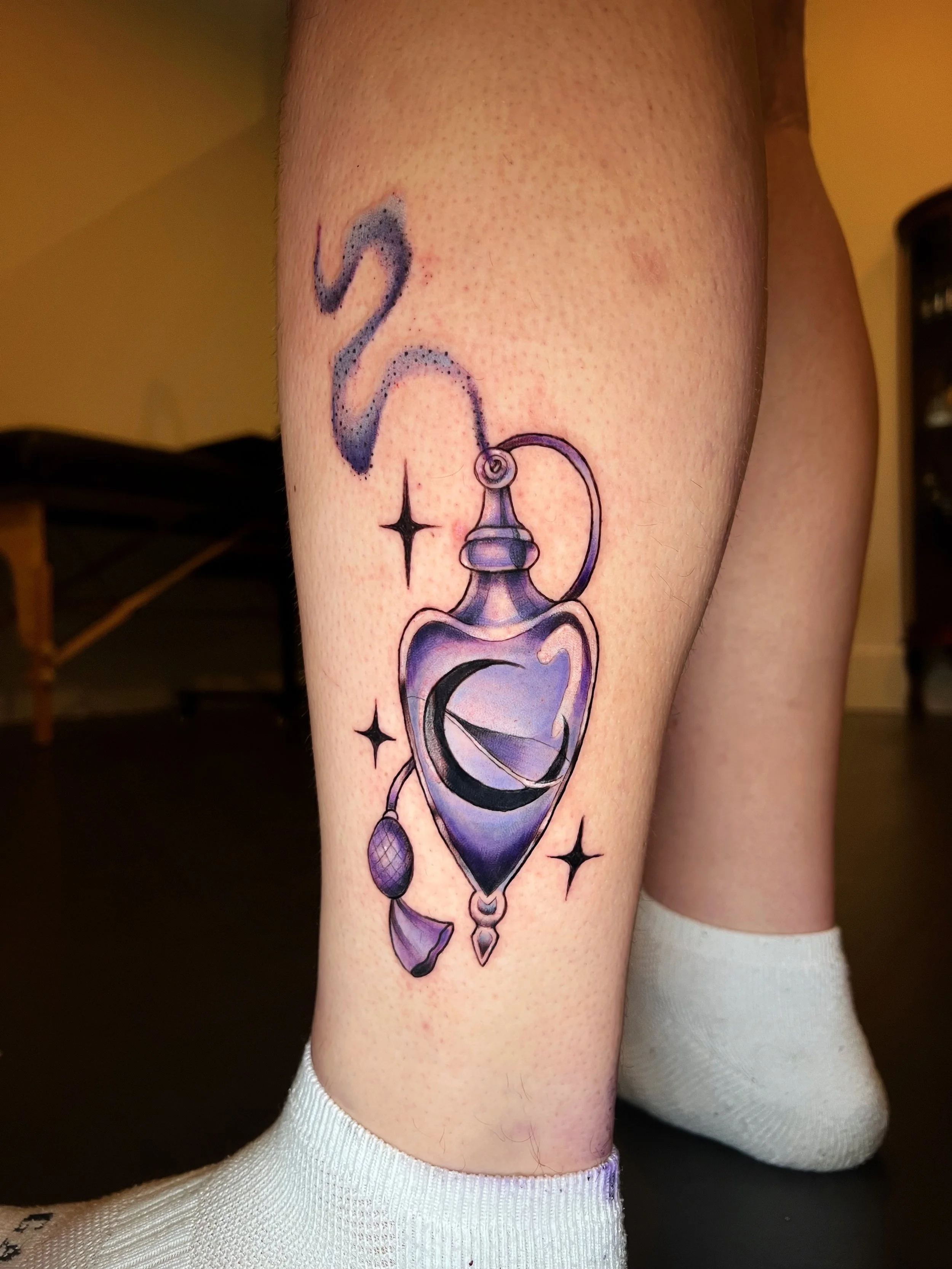 Tattoo of a purple and black spell jar with stars and smoke on a person's thigh, with white socks visible.