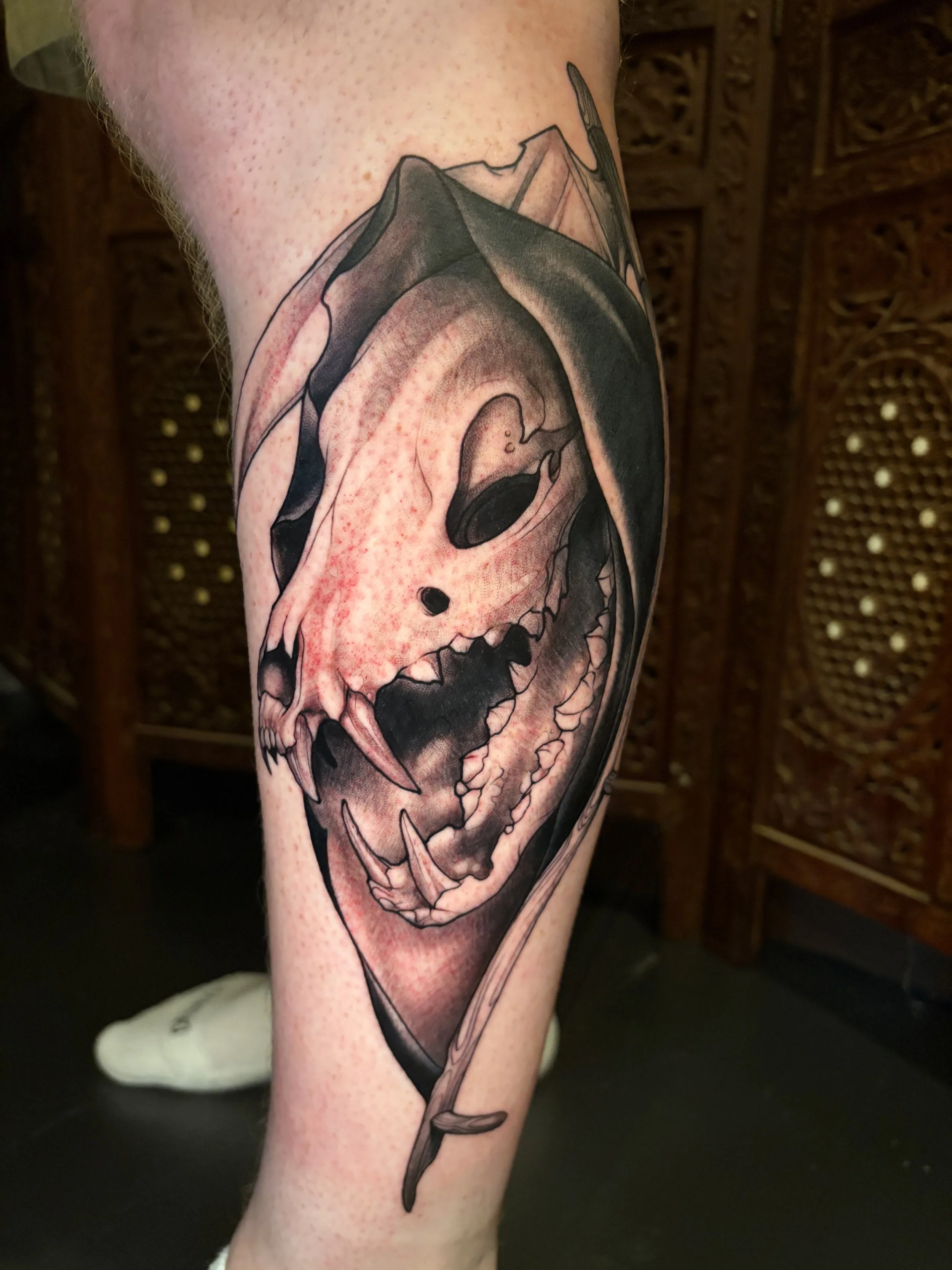 Tattoo of a skull with a sword through it on a person's arm.
