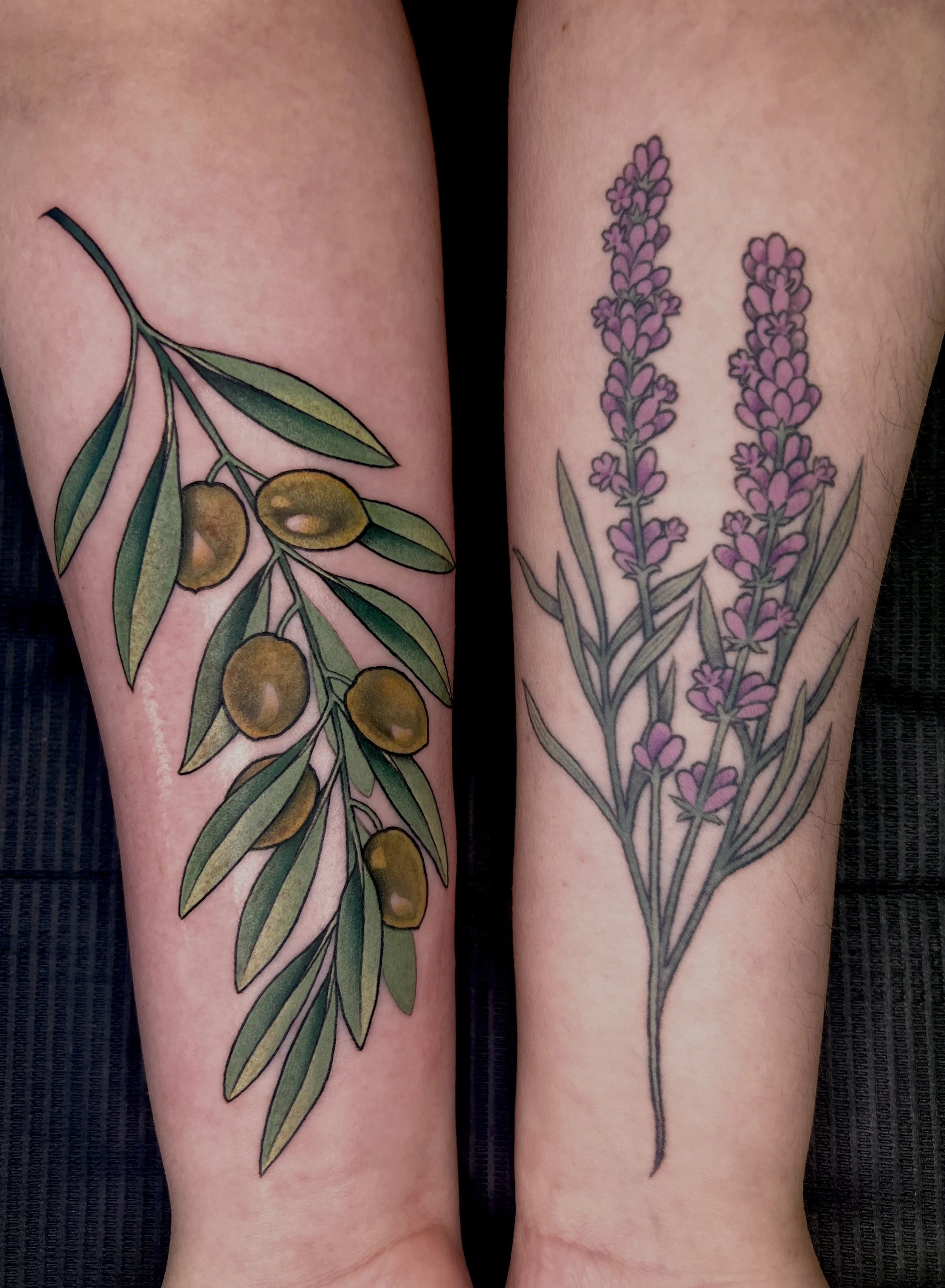 Two tattoos on forearms featuring lavender flowers with green stems and leaves, one with purple lavender and one with yellowish-green olives on an olive branch.