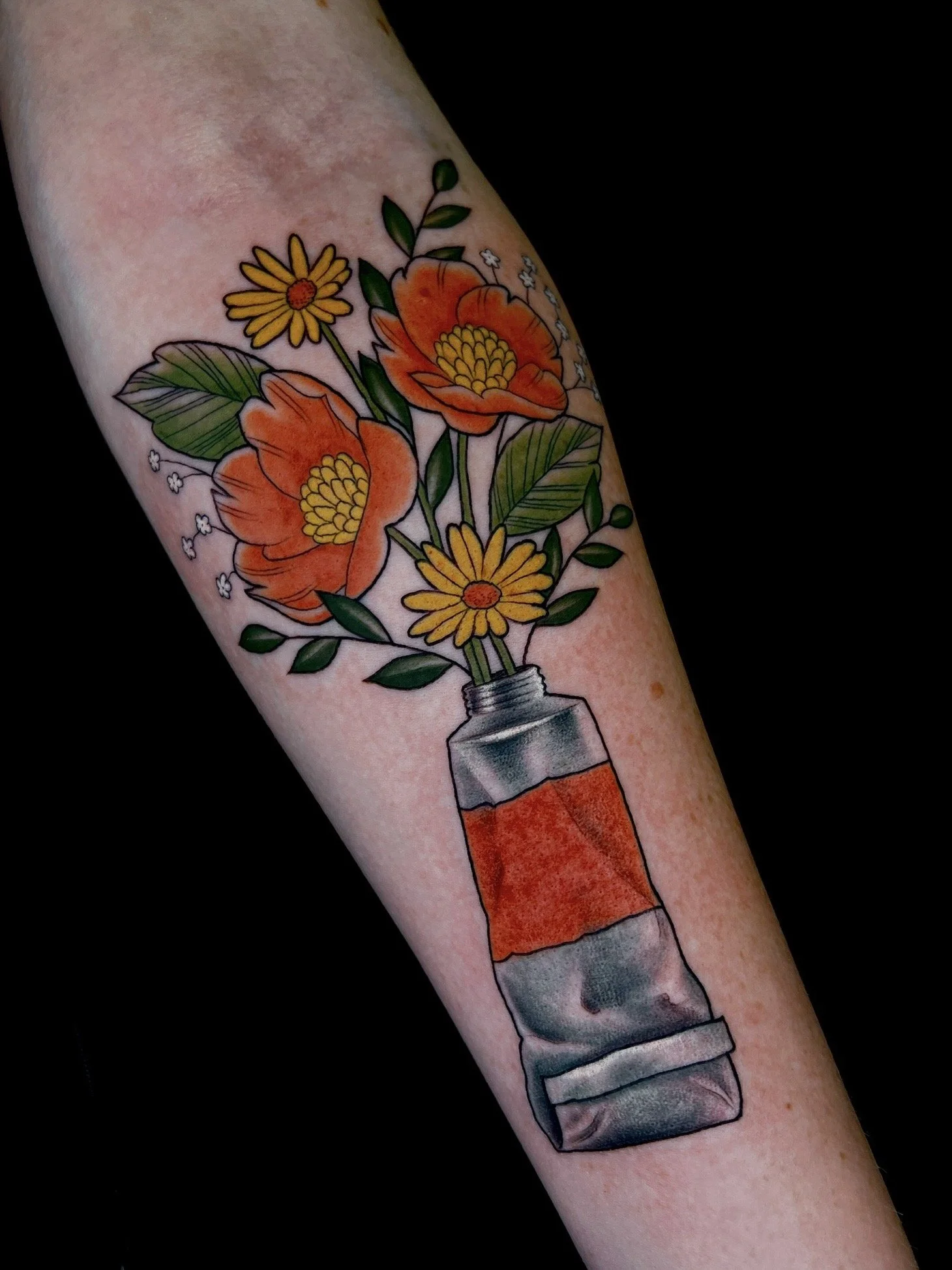 A tattoo of a watering can with a bouquet of orange and yellow flowers and green leaves.