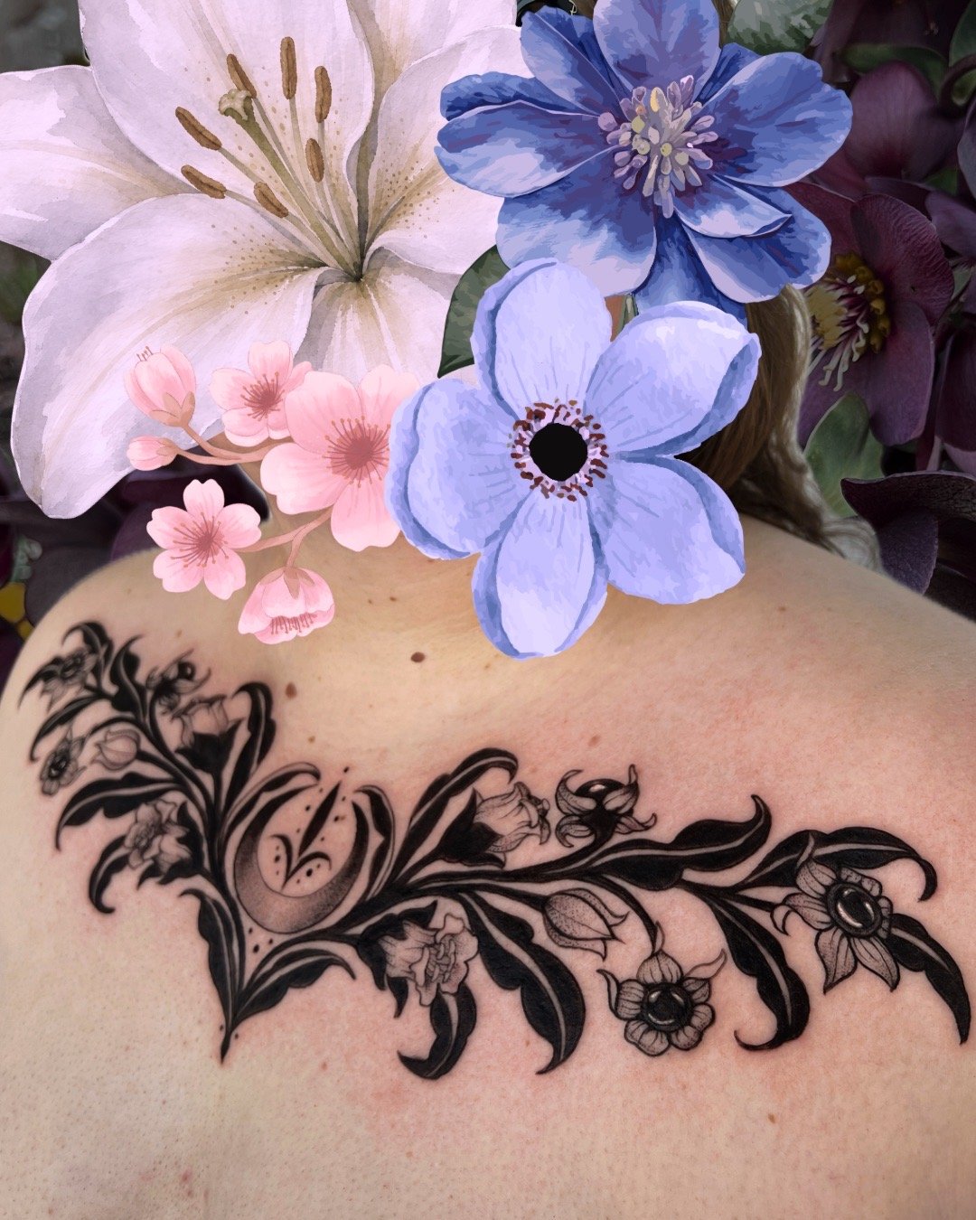 Tattoo of black floral design on skin with large pink and blue flowers and an assortment of smaller pink flowers nearby.