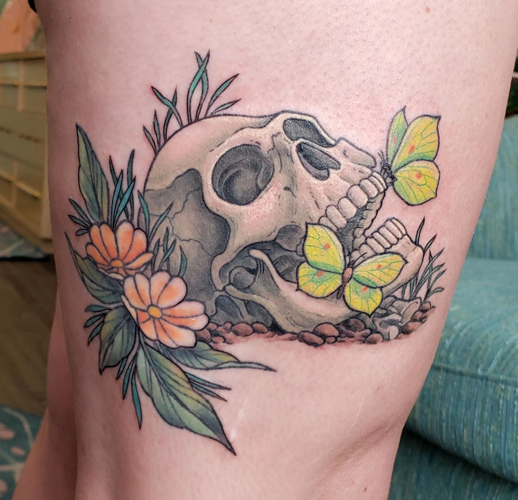 Tattoo of a skull with flowers and a butterfly on the skin