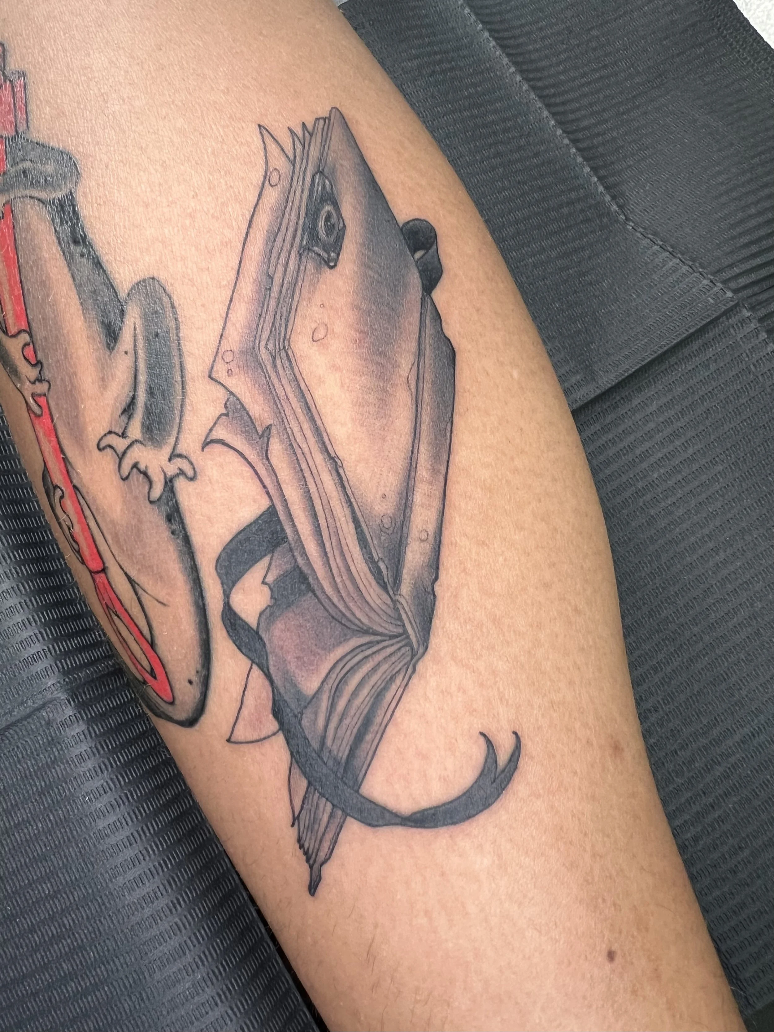 A tattoo of a detailed bullet with a dragon wrapped around it on a person's upper arm.