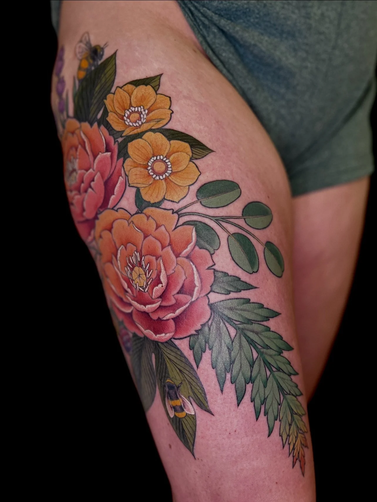 A tattoo of orange and pink flowers and green leaves on a person's upper arm.