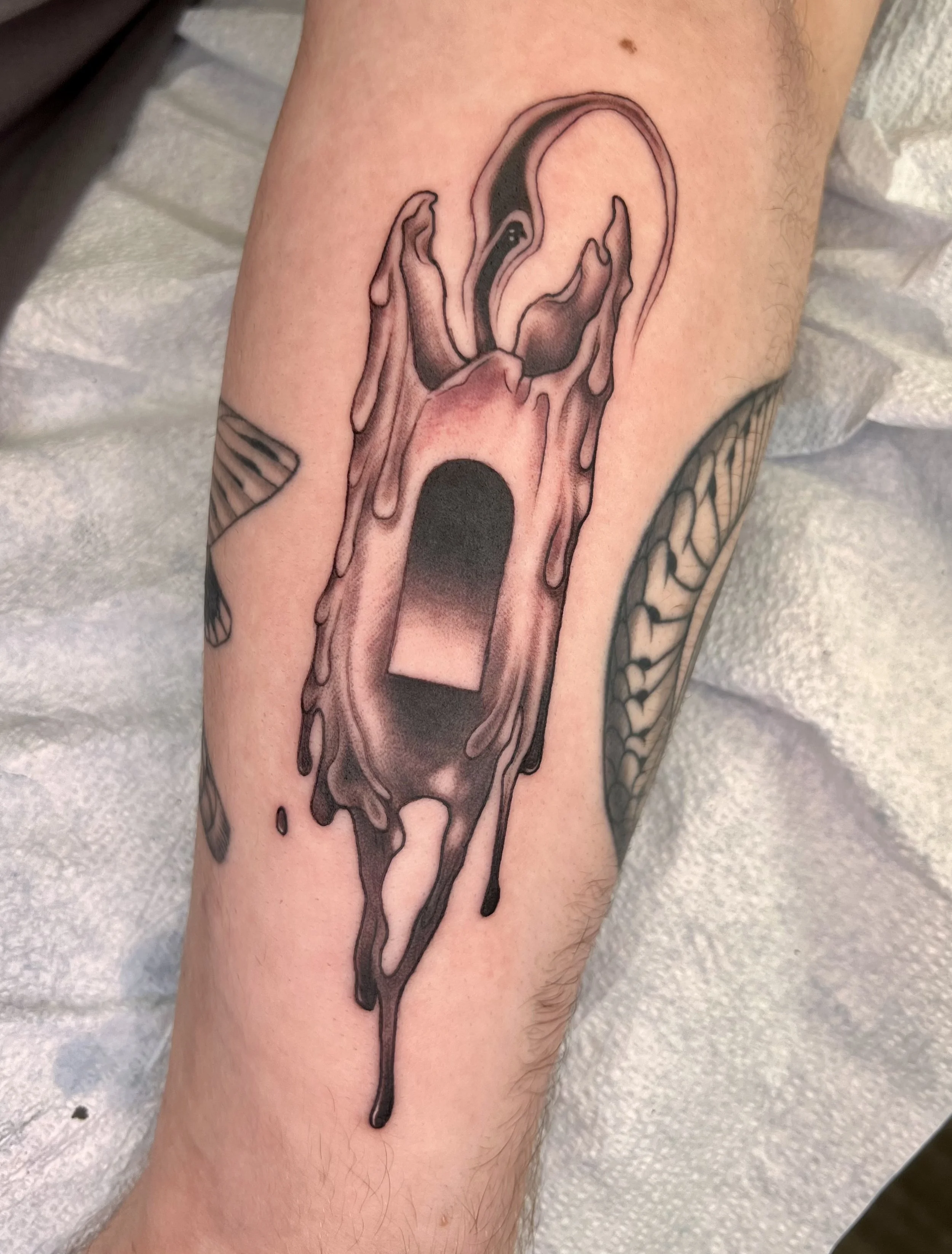 Tattoo of a melting ice cream cone on a person's forearm.
