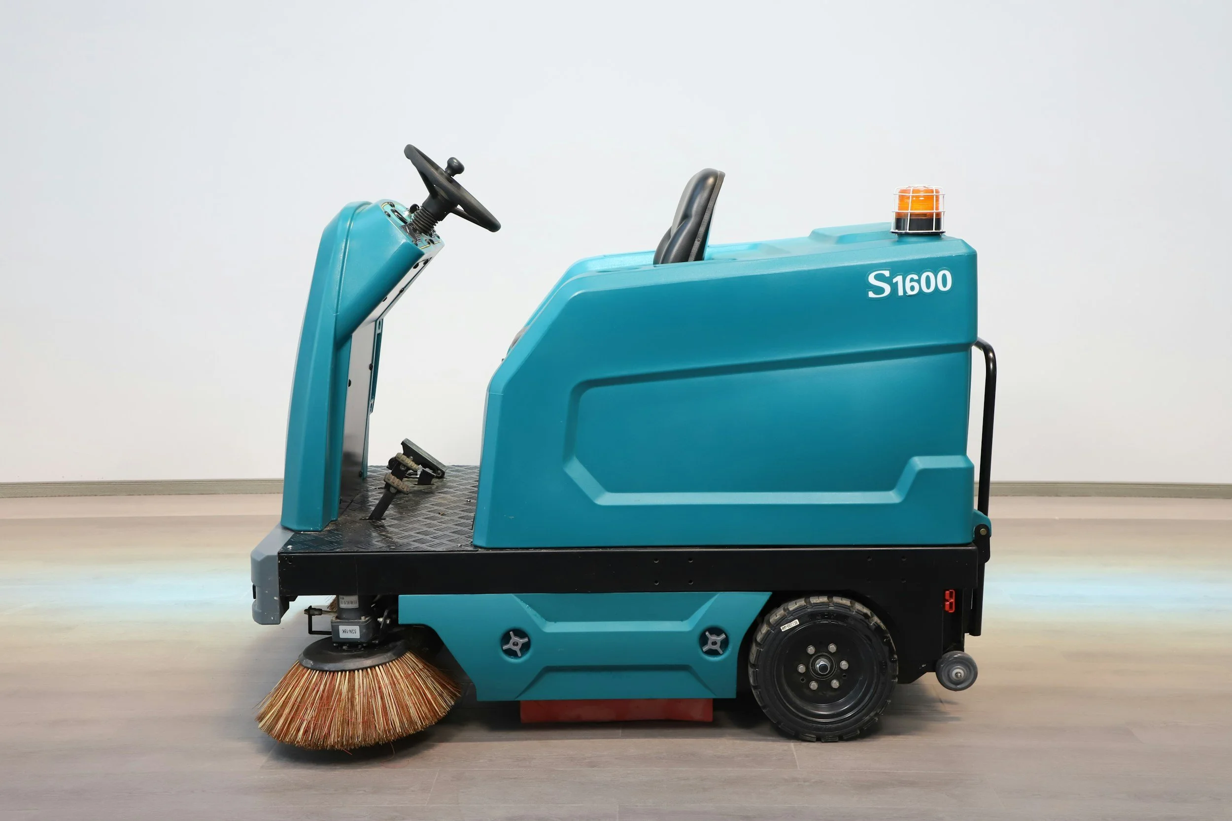 Automated cleaning machine with a broom sweeping the floor