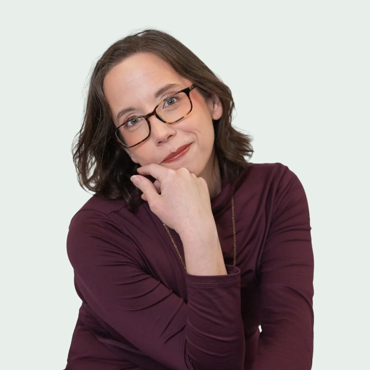Alex Hughes Capell smiling and wearing dark purple sweater and glasses.