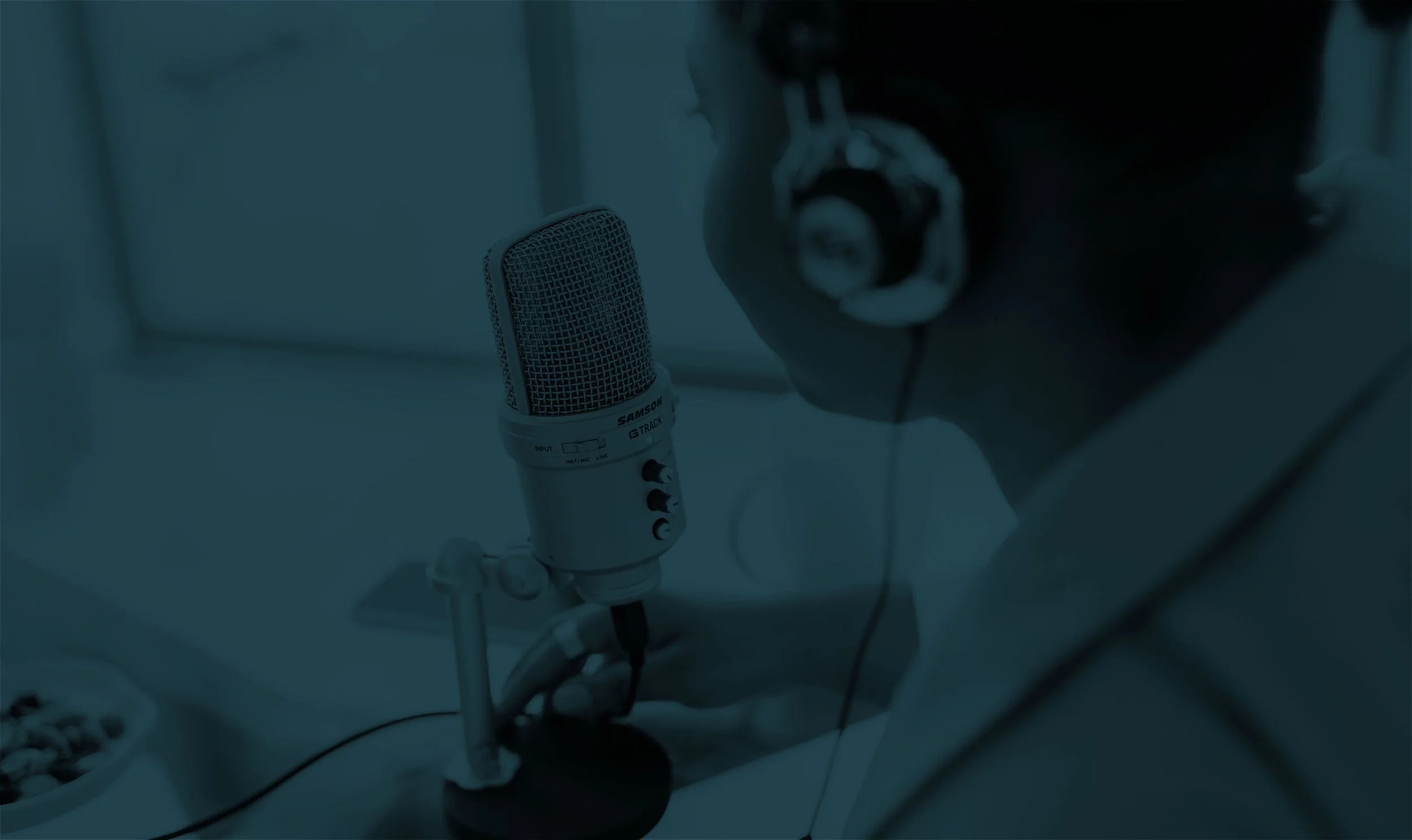 Woman wearing headphones and speaking into a microphone to record her podcast.
