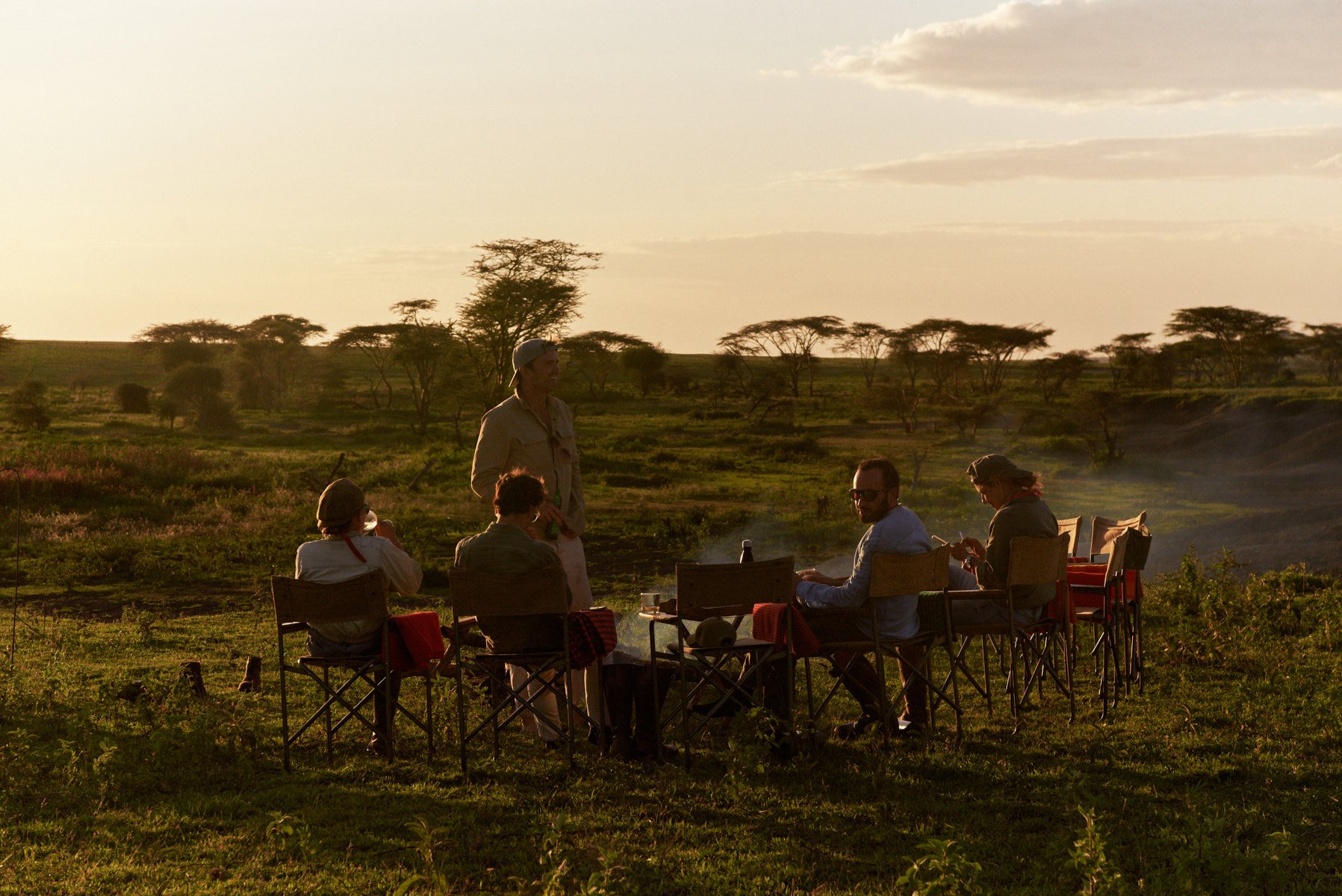 Guests gathered around the fire at sunset on safari