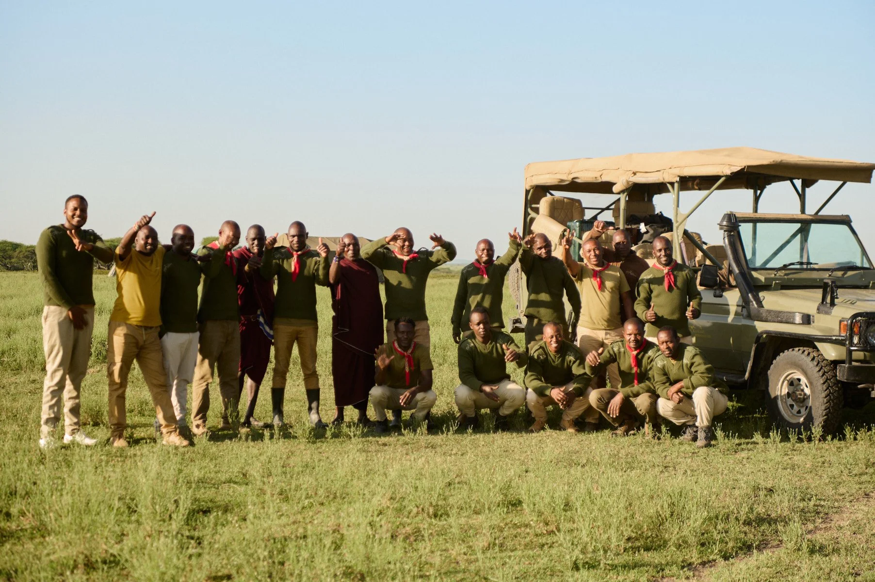 Tanzania Horse Safaris team celebrating beside a safari vehicle