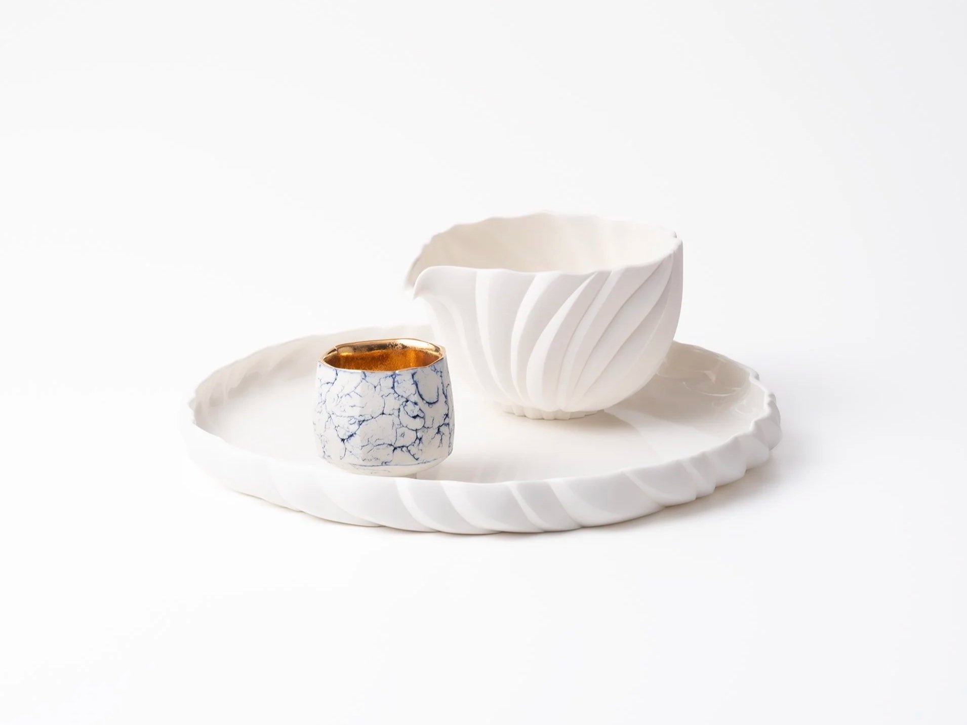白い陶器の花瓶とカップが白い陶器の皿に置かれている。