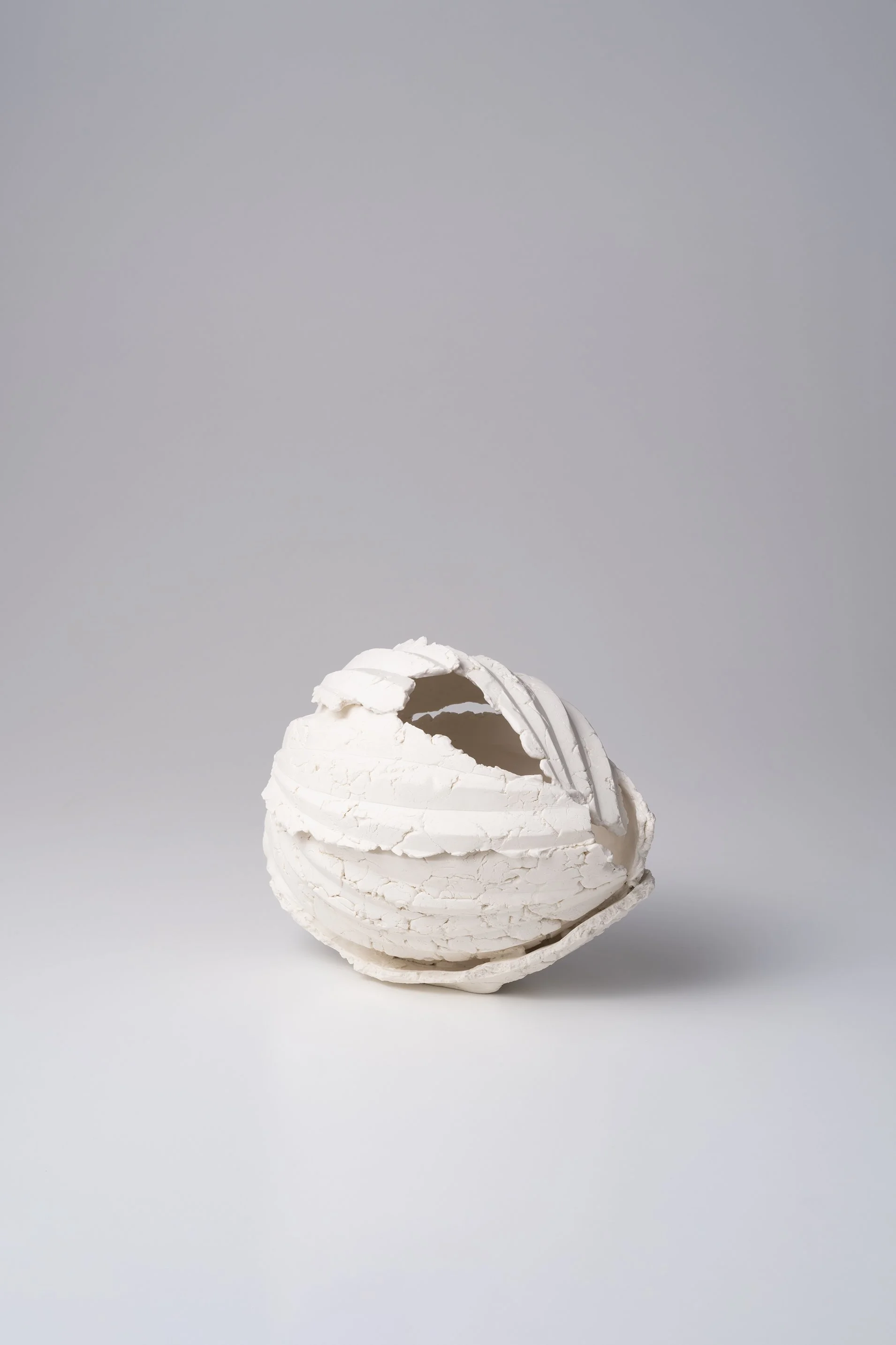 白い割れた卵の殻を逆さにして置いたアート作品。背景はグレー