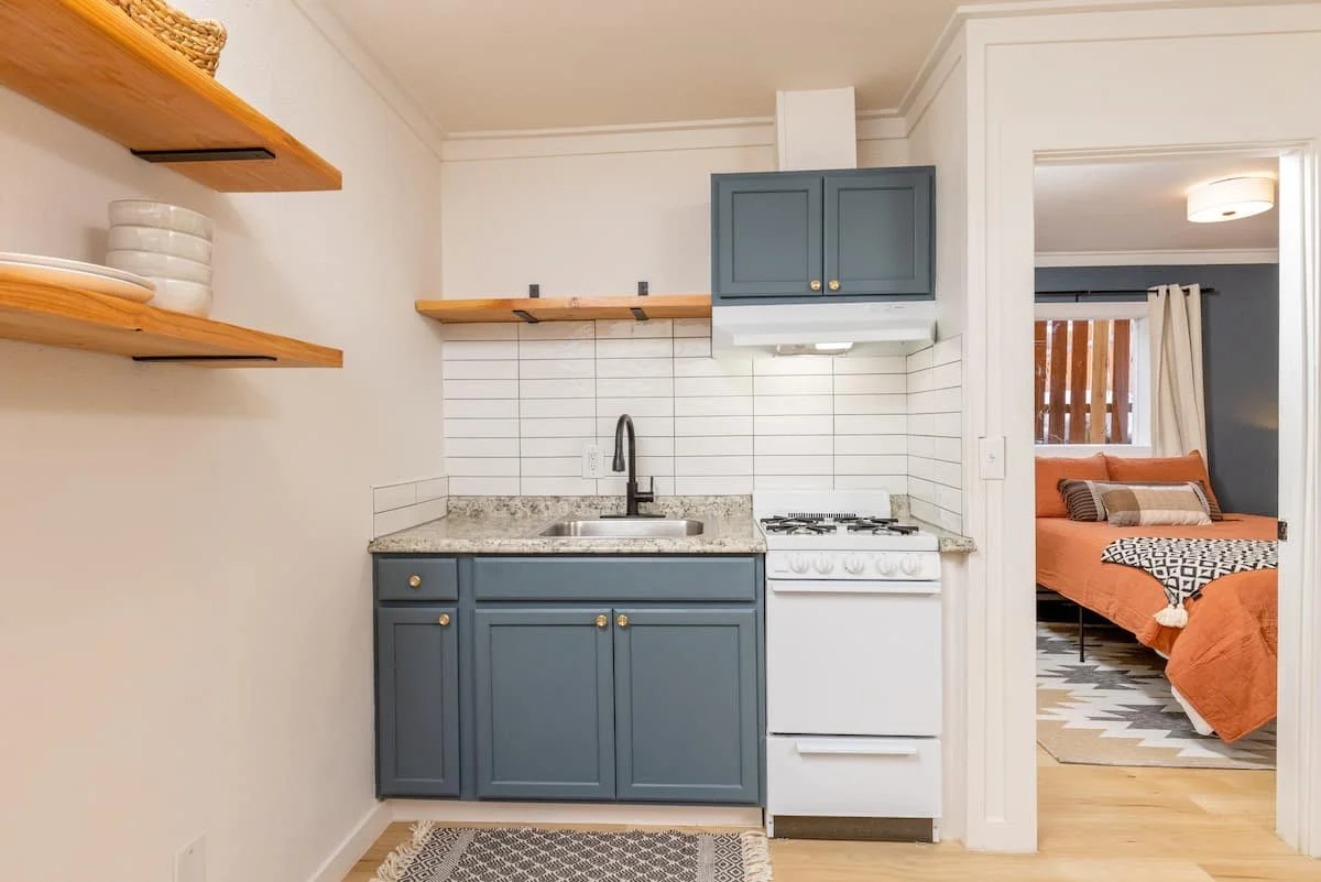 Renovated apartment kitchen with blue cabinetry and open shelving at Iowa Flats in Anchorage, Alaska.