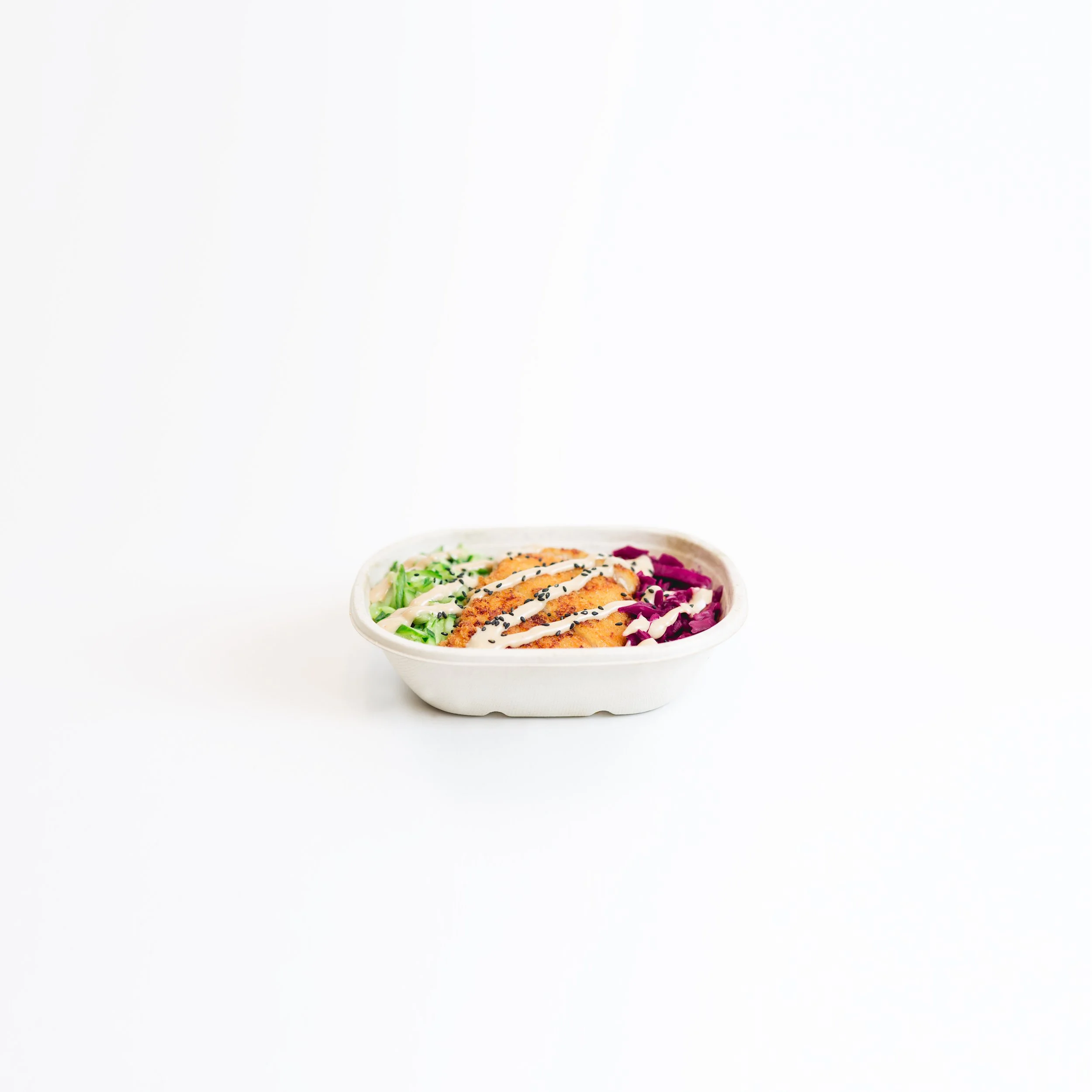 A bowl of rice with breaded and fried chicken strips topped with white sauce, sprinkled with sesame seeds, and garnished with chopped green onions and purple cabbage.