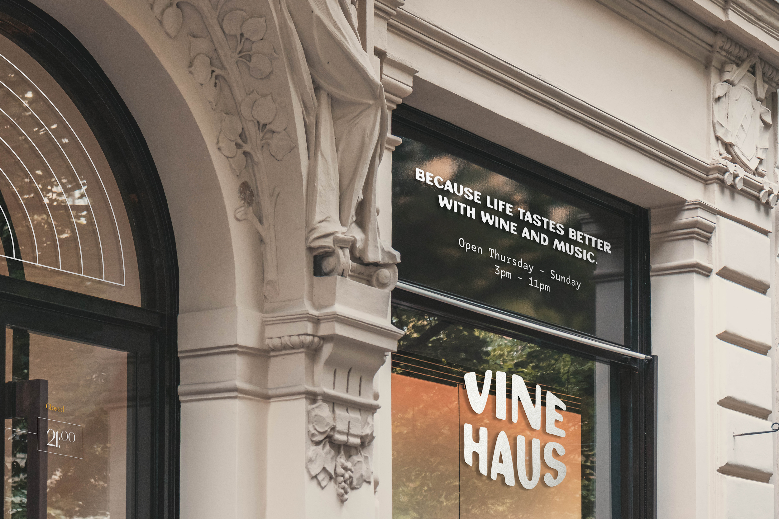 Close-up of a building facade with ornate architectural details and a digital sign displaying business hours, indicating a cafe or similar establishment.
