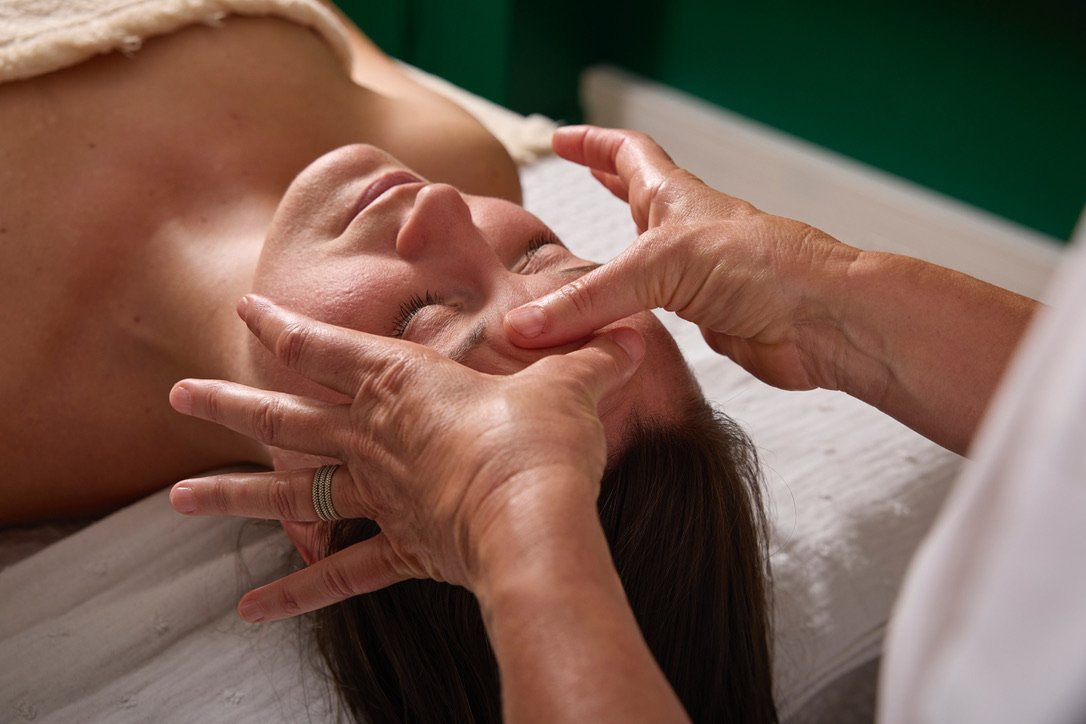 Une femme reçoit un massage du visage dans un centre de soins.