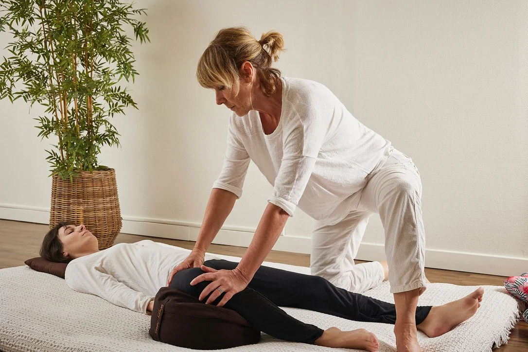Une femme faisant un massage Shiatsu à une autre femme allongée sur un futon.