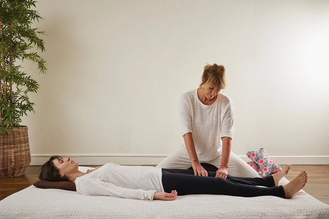 Une femme faisant un massage Shiatsu à une autre femme allongée sur un futon.