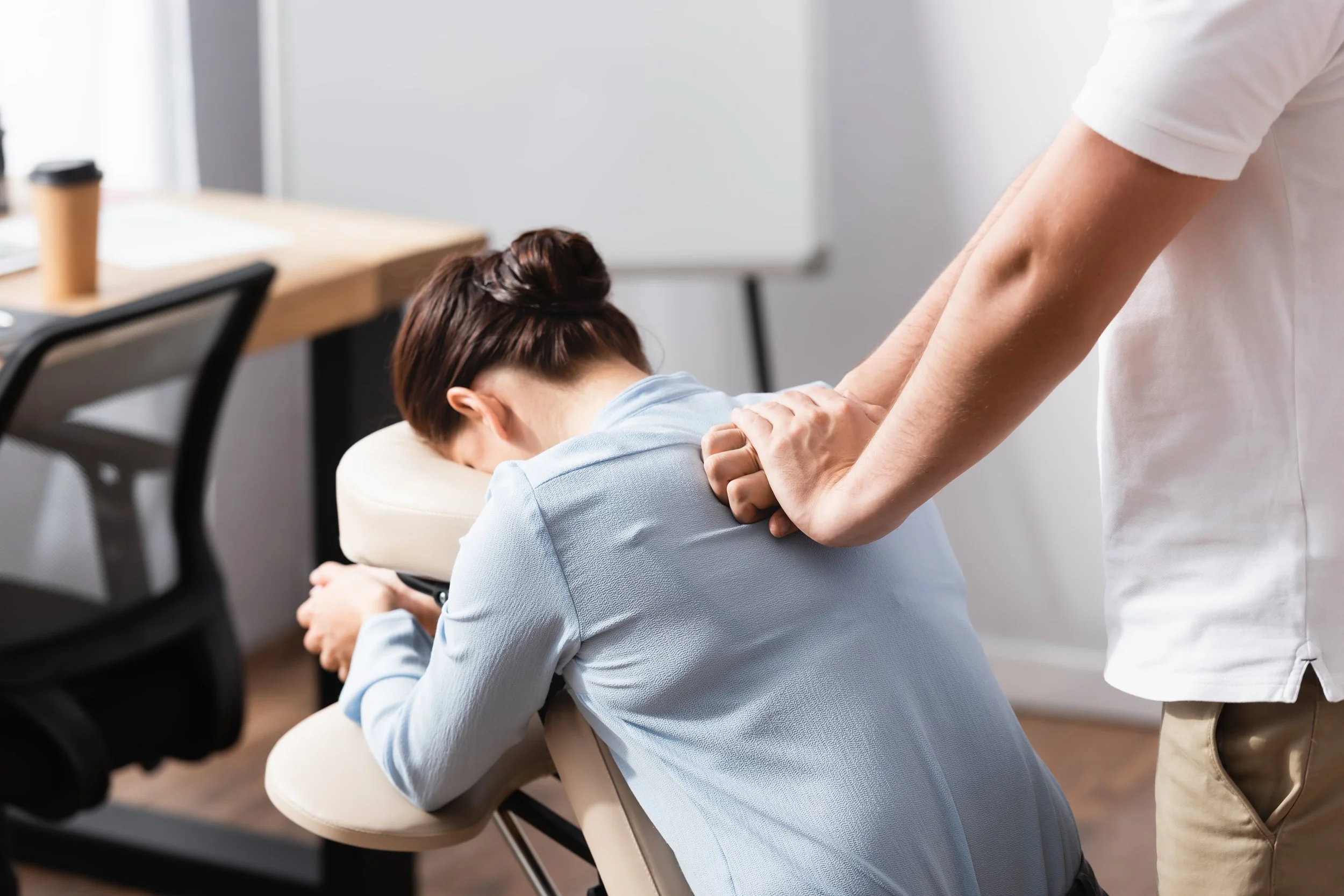 Une personne reçoit un massage de la part d'un praticien dans un environnement de bureau.