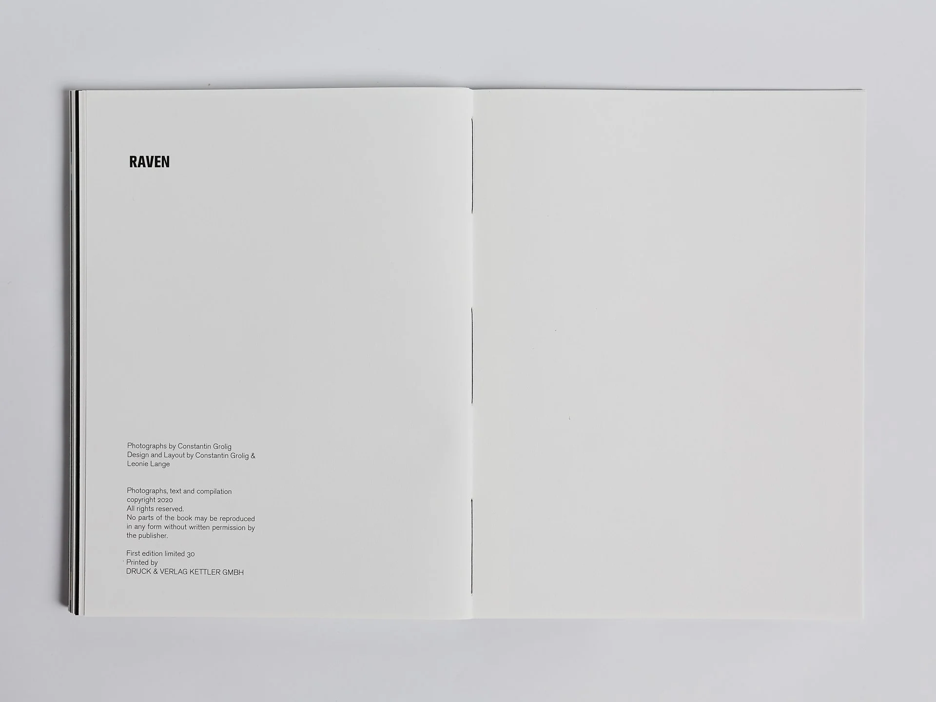 Öffentliches Fotobuch mit weißer Seite, Überschrift 'RAVEN' in großer Schrift links oben, kleine Fußnoten am unteren Rand, ein Teil der Buchbindung sichtbar links, Text in schwarzen Buchstaben.