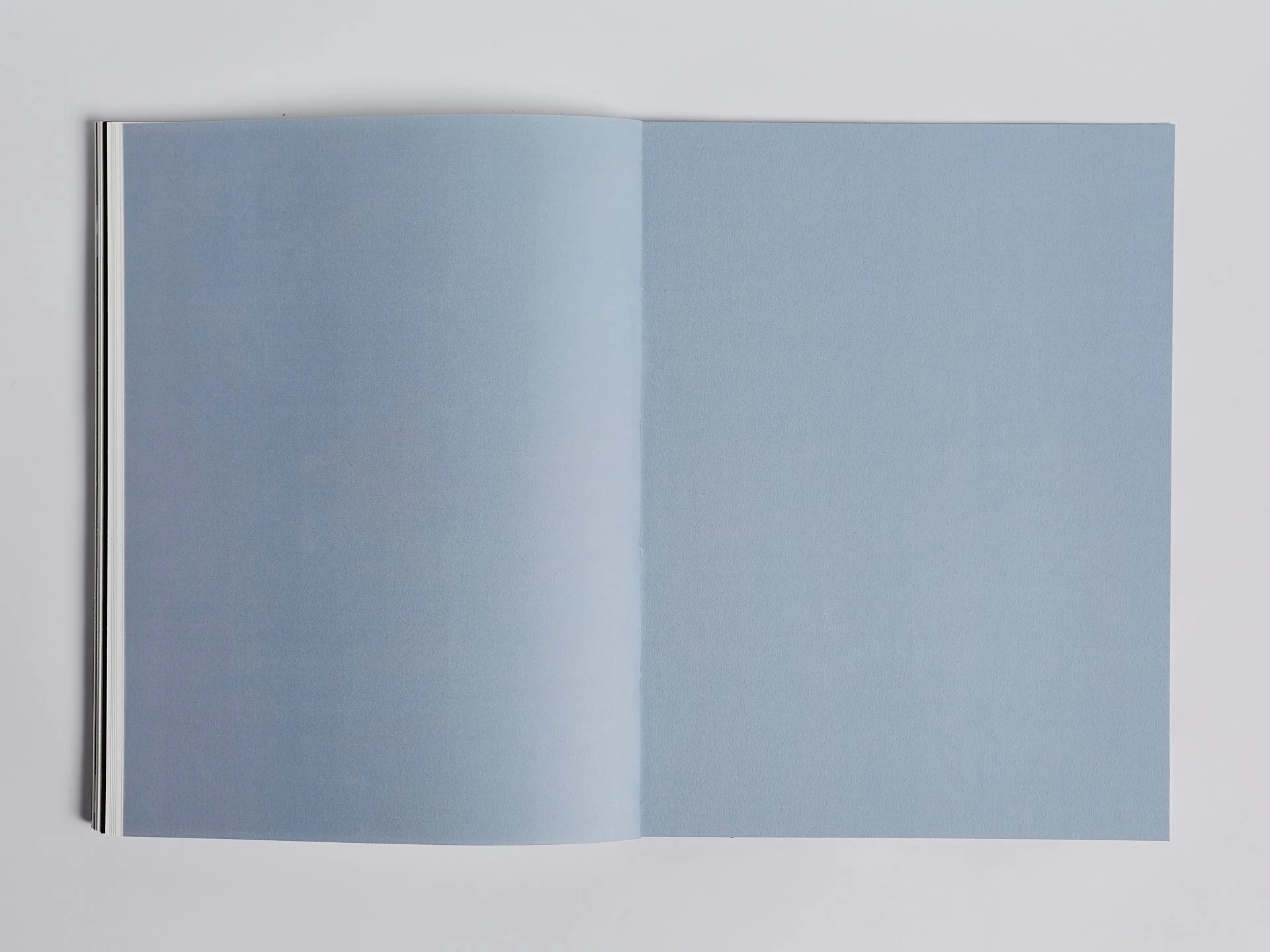 Offene Zeitschrift mit blauen Seiten auf weißem Hintergrund.