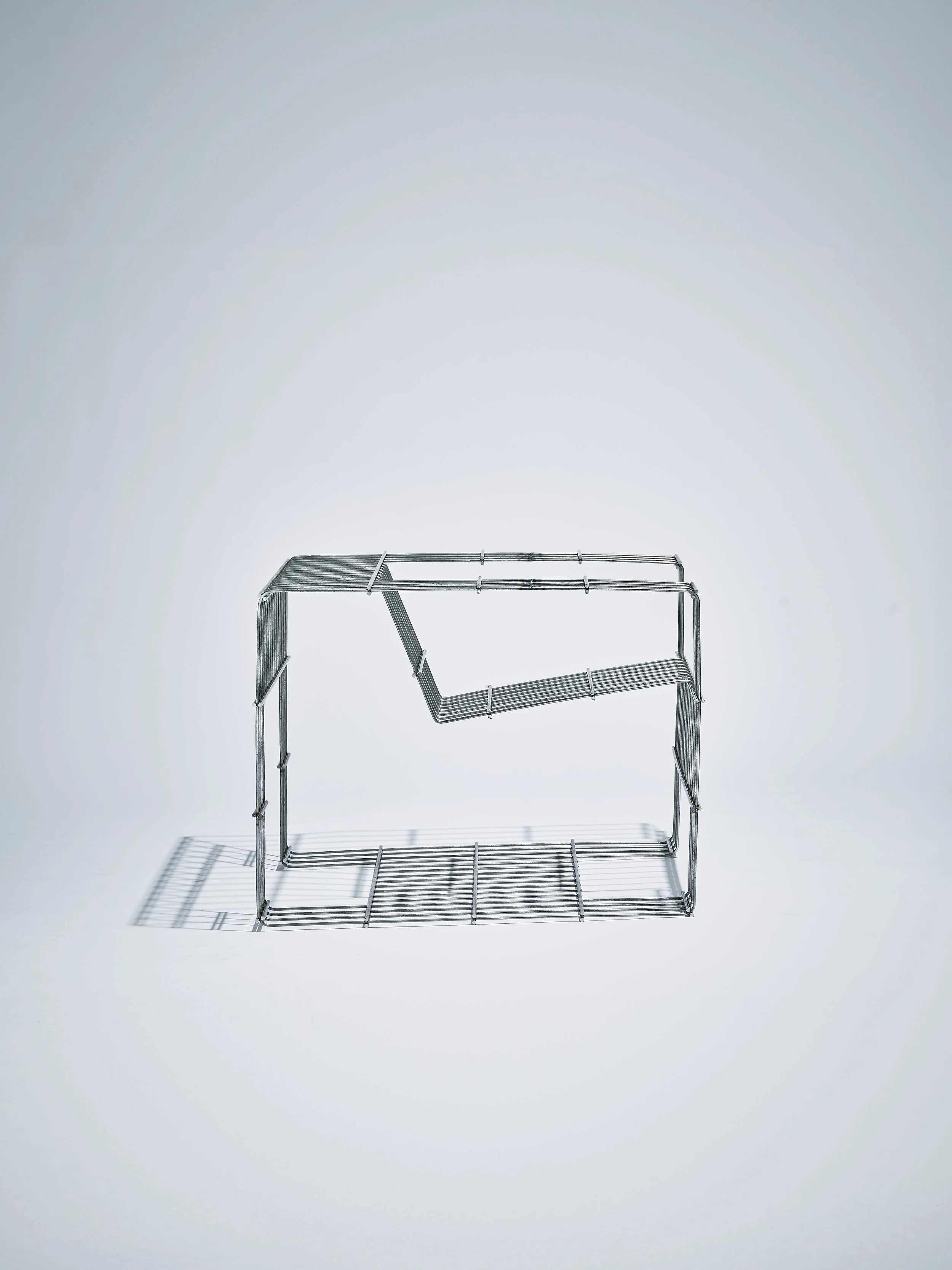 Ein leeres, aus Metall gefertigtes Gestell in einer minimalistischen, weißen Umgebung.