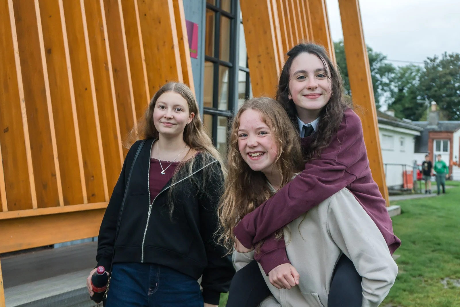 Three young girls smiling outdoors in front of Doune's DDYP pavillion. 