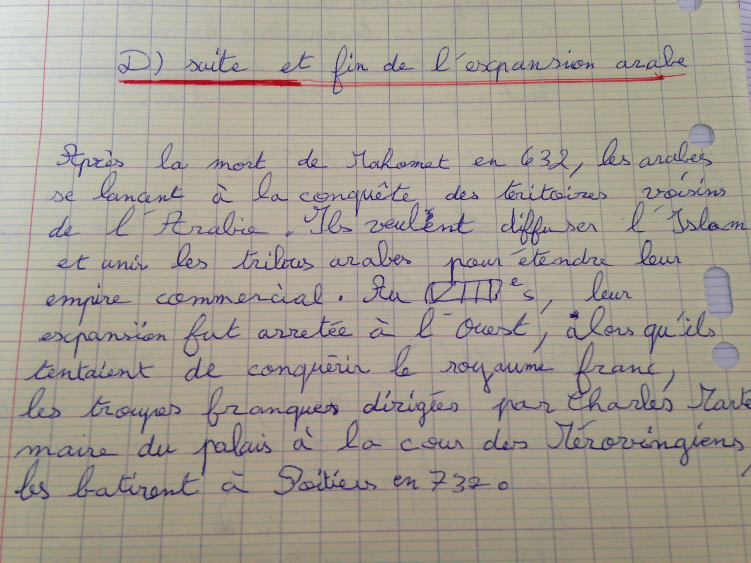 Page de cahier avec écriture en cursive en bleu et en violet sur du papier à carreaux. La ligne supérieure est soulignée en rouge.