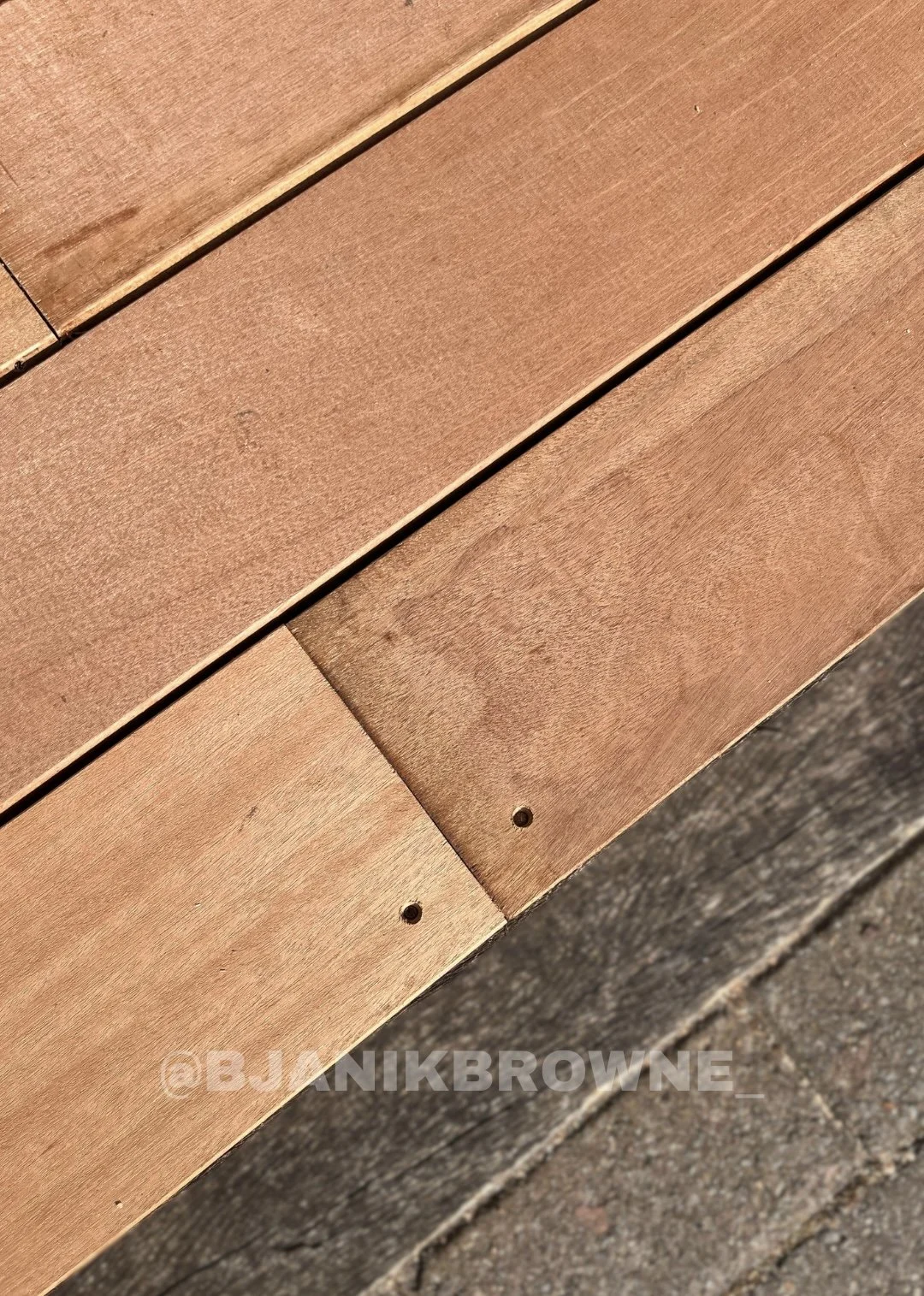 Close-up of wooden fence panels with a reddish hue, showing the texture and small screw holes.
