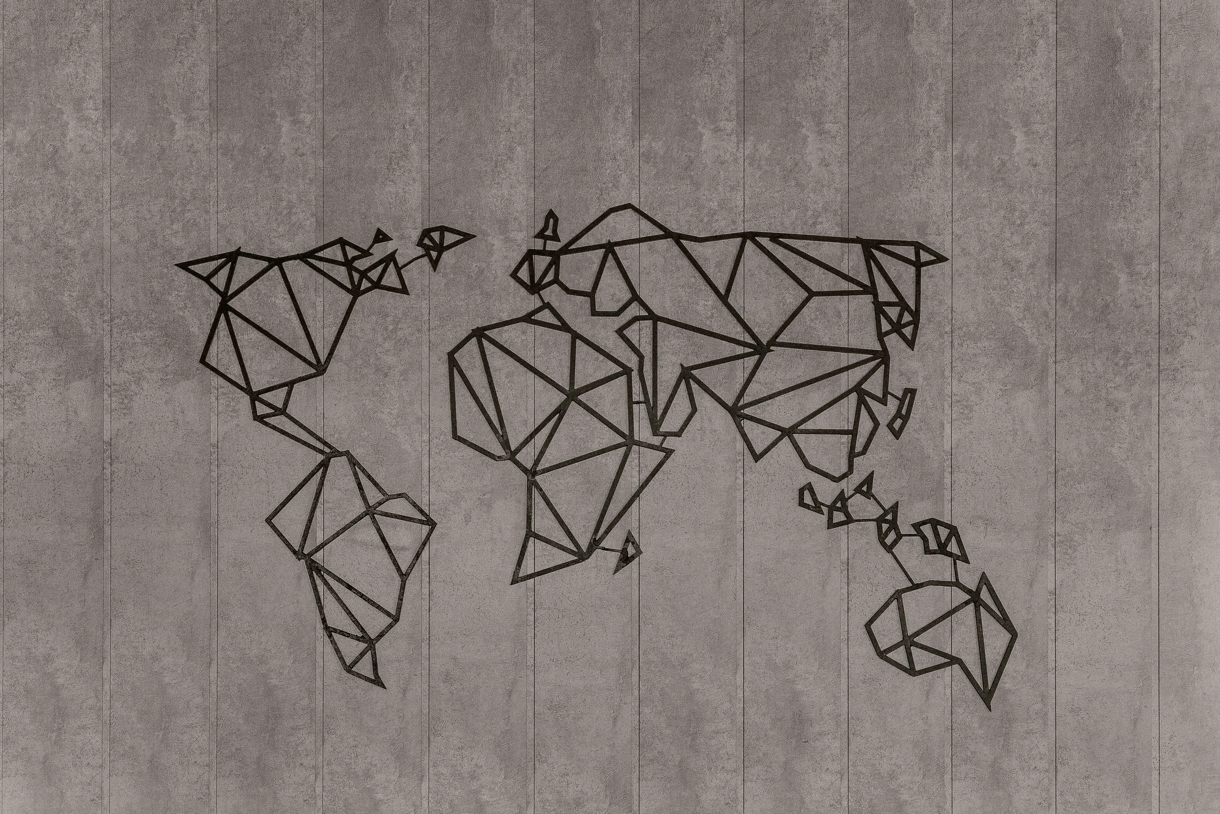 Metal wall art in the shape of a world map on a textured concrete wall.