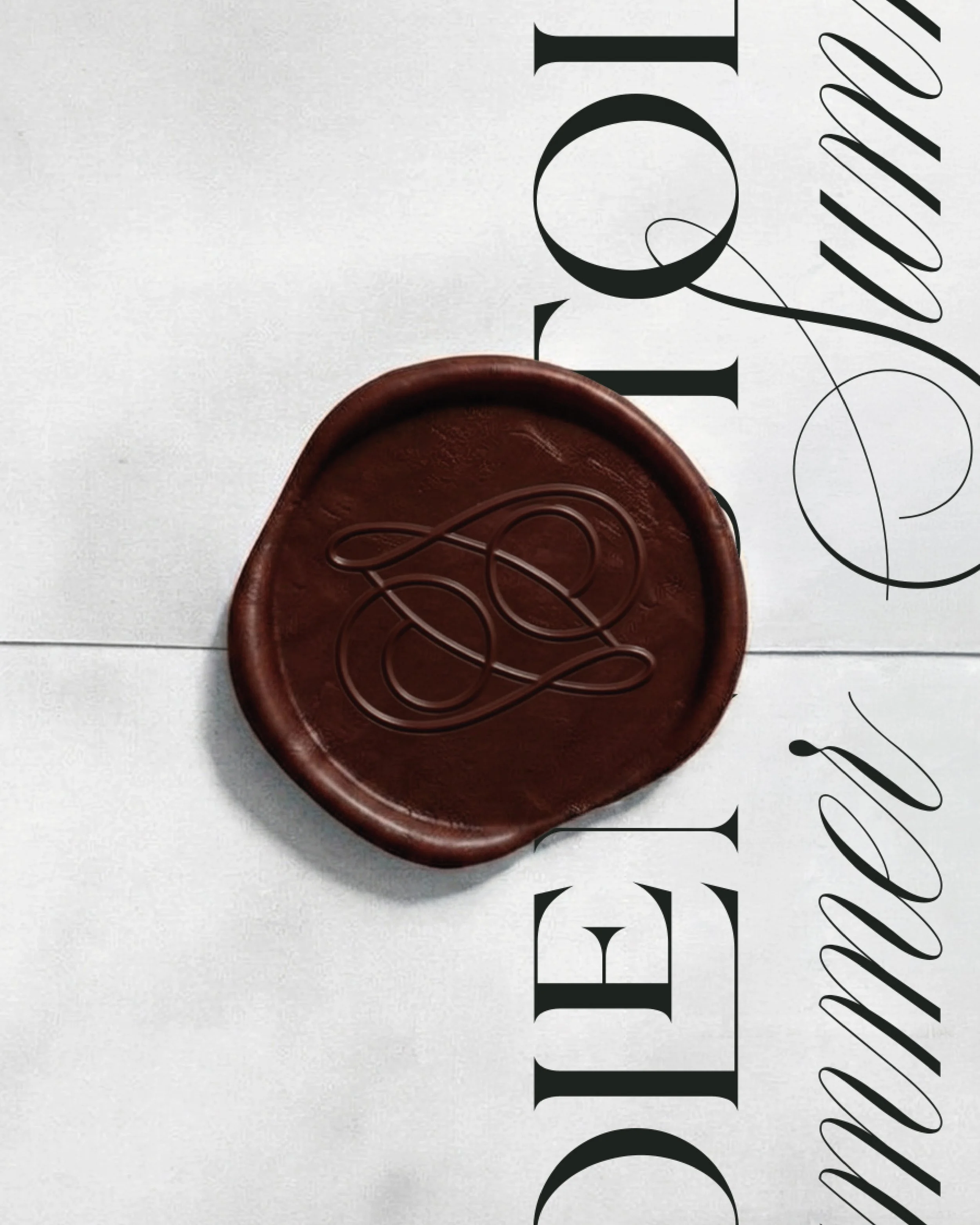 Un cercle en bois ou en plastique marron portant un motif en forme de boucle stylisée de couleur sombre, posé sur une surface blanche. Le fond comporte un texte partiellement visible en grandes lettres noires.