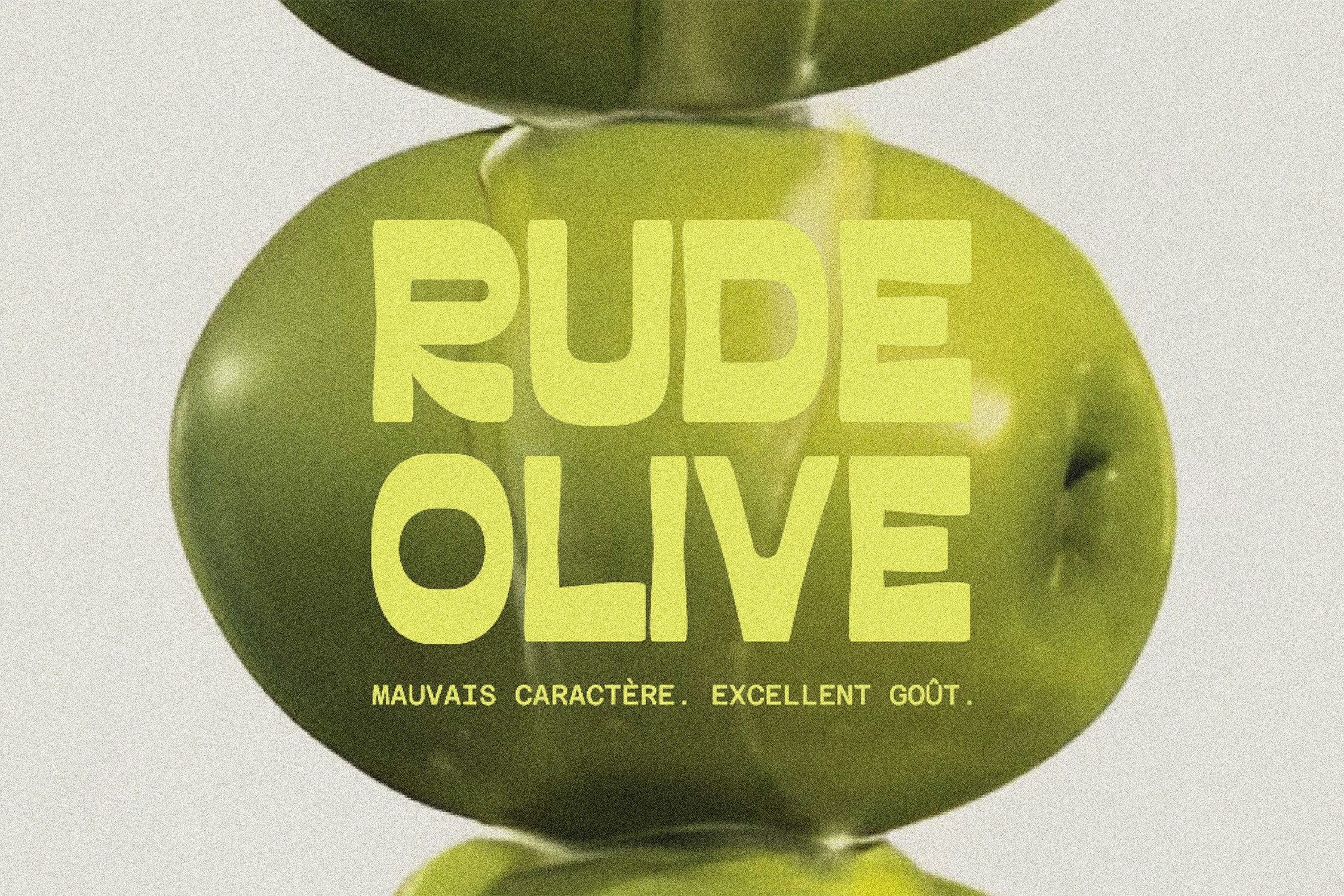 Une image d'un avocat vert avec le texte » RUBE OLIVE » en jaune. Le texte en dessous indique : »MAUVAISE CARACTÈRE. EXCELLENT GOÛT».