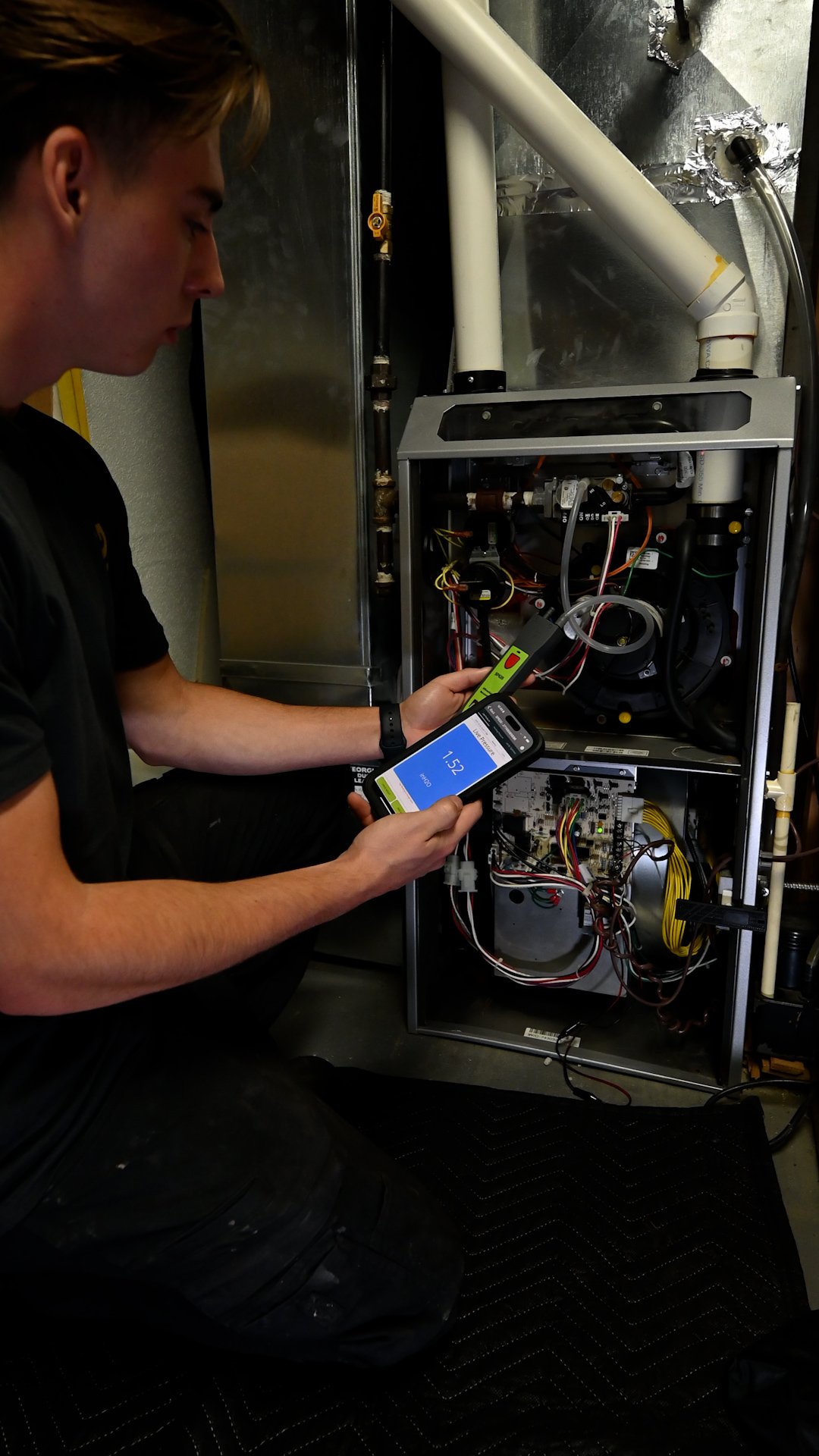 Technician repairing a water heater, working on electrical components inside the unit.