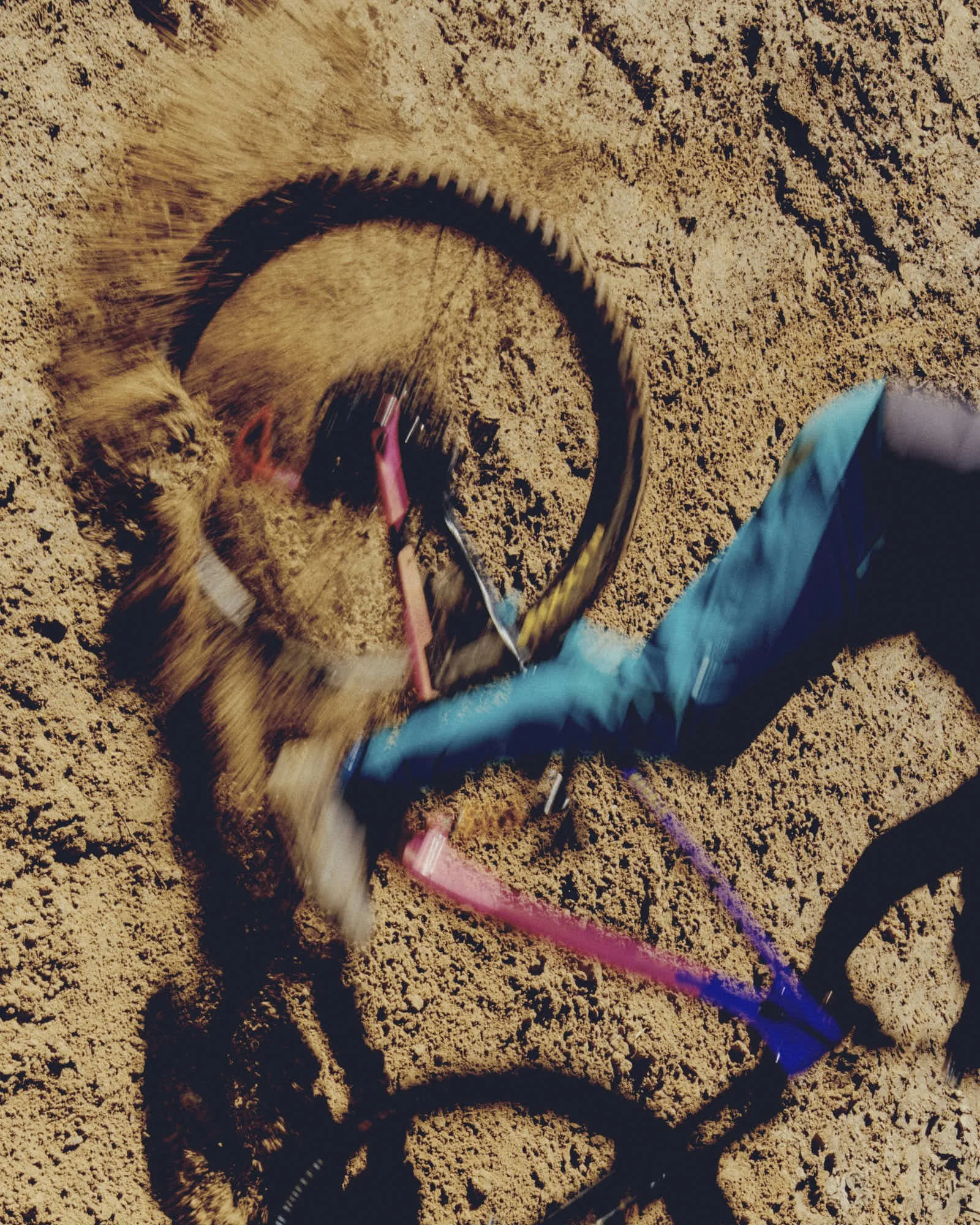 A person using a jump rope on sandy ground, with part of their body visible on the right side wearing blue athletic shorts.