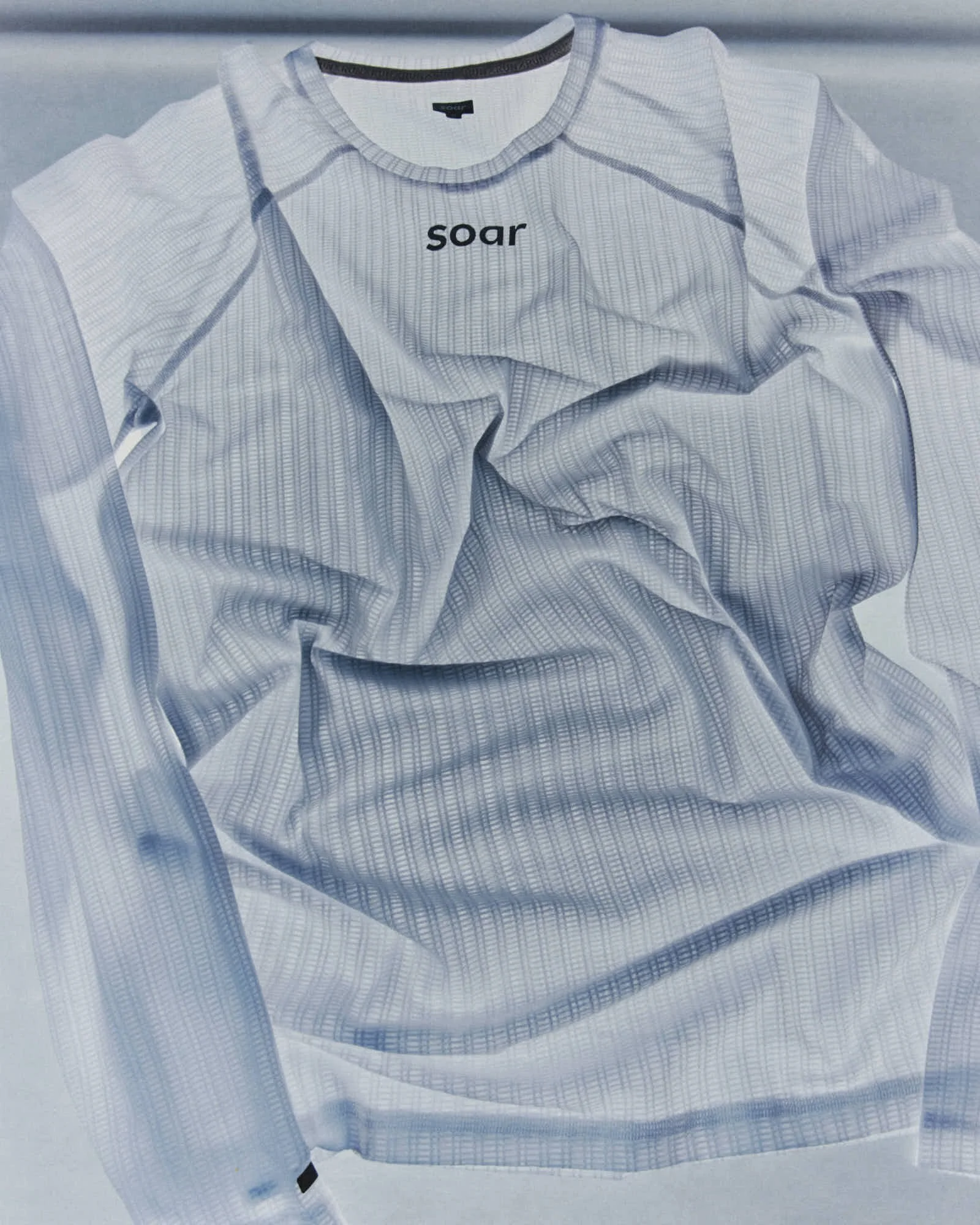 A white shirt with thin, vertical gray stripes and the word 'soar' printed in black on the front.